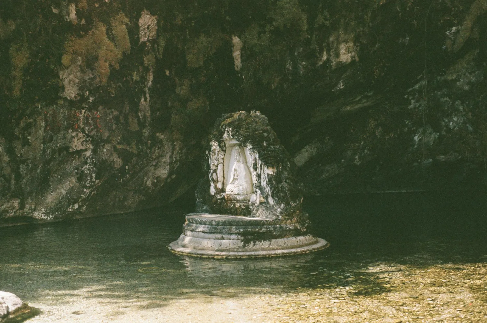 A serene carved Buddha sculpture in a natural cave setting, capturing spiritual tranquility.