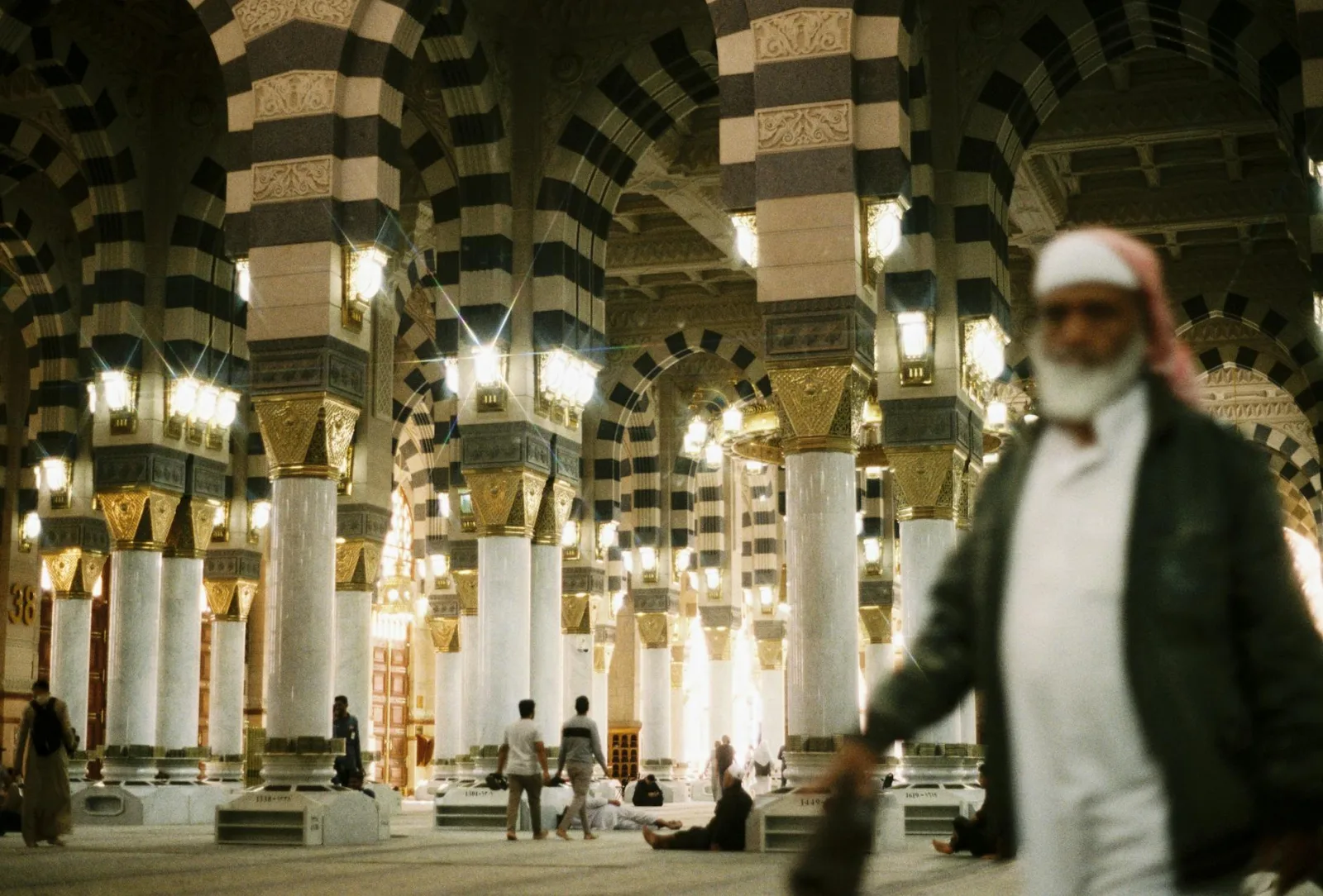Interior view of Al-Masjid an-Nabawi in Madinah, showcasing intricate architecture and Muslim worshipers.