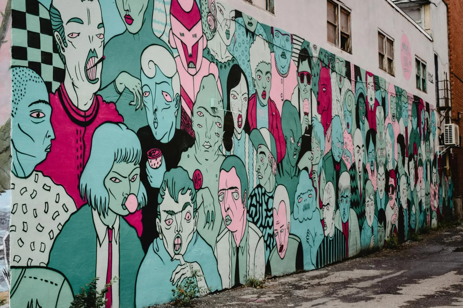 Colorful street art mural showcasing diverse faces in a Montreal alleyway.