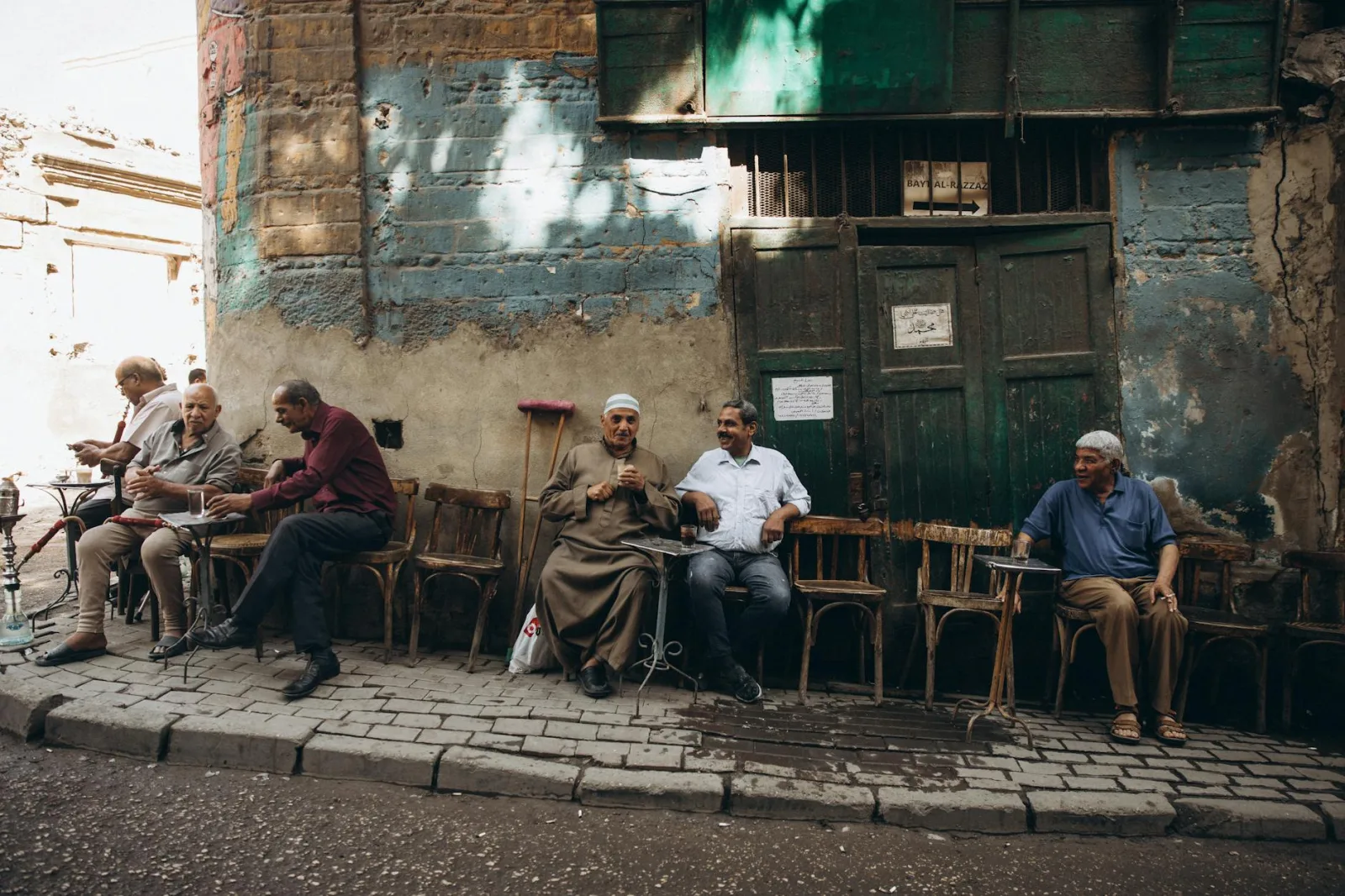 Men gathering at an outdoor café in Cairo's Al-Darb Al-Ahmar district on a sunny day.