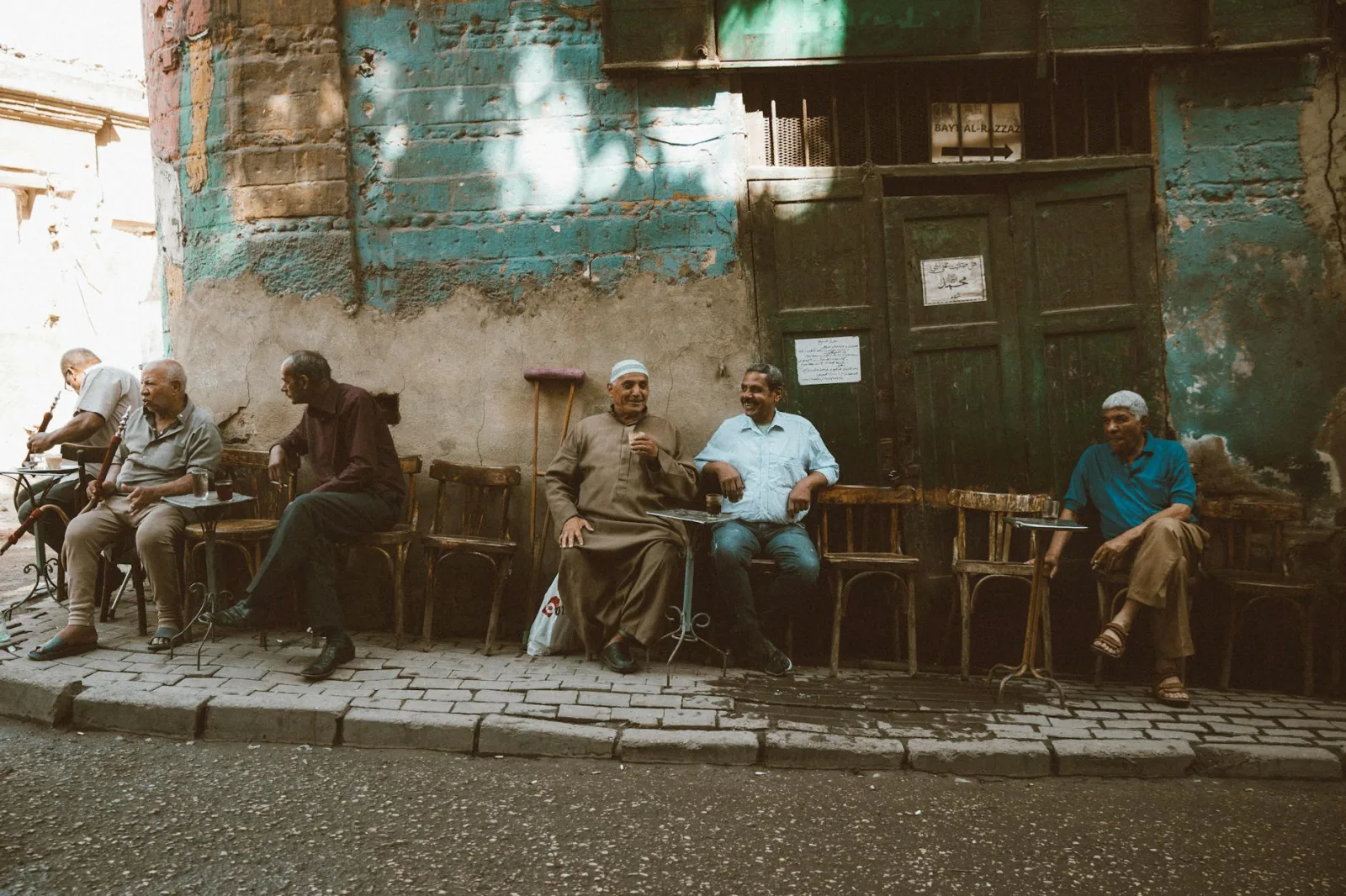 Local men enjoy a casual gathering outside a café in Cairo's historic Al-Darb Al-Ahmar district.