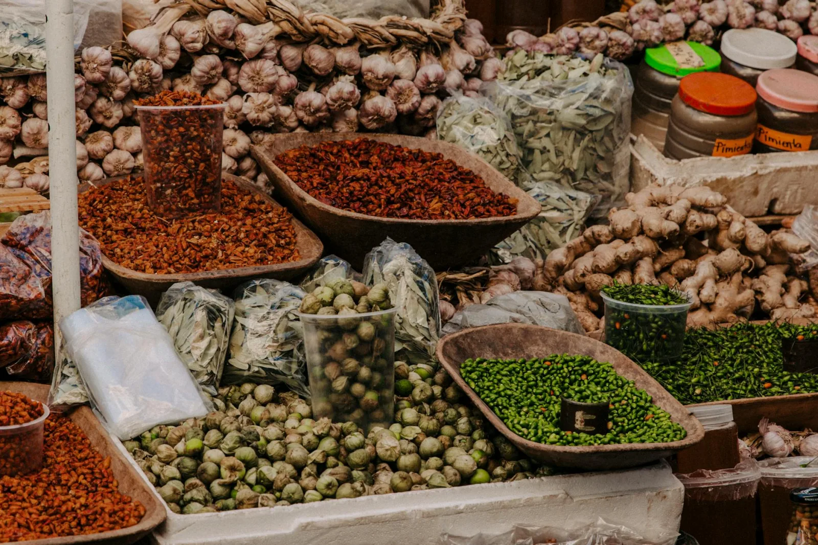 Vibrant display of fresh vegetables, spices, and herbs at a bustling outdoor market.