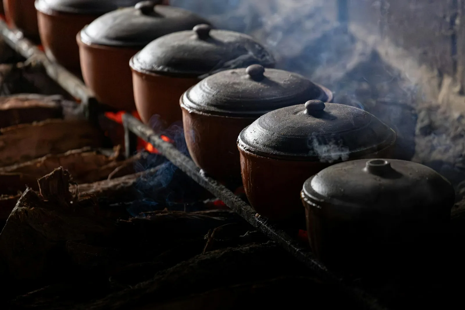 Steaming clay pots cooking over an open fire in Vietnam.