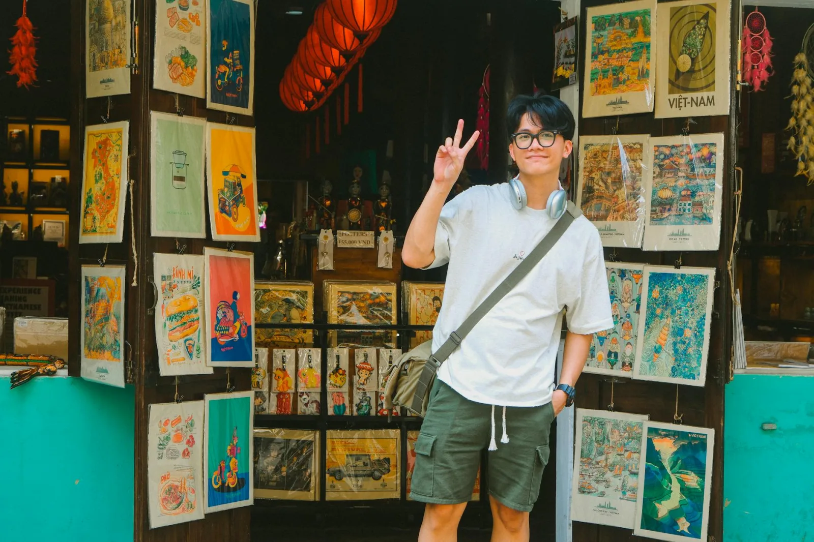 A young man poses with a peace sign outside a vibrant Vietnamese souvenir shop.
