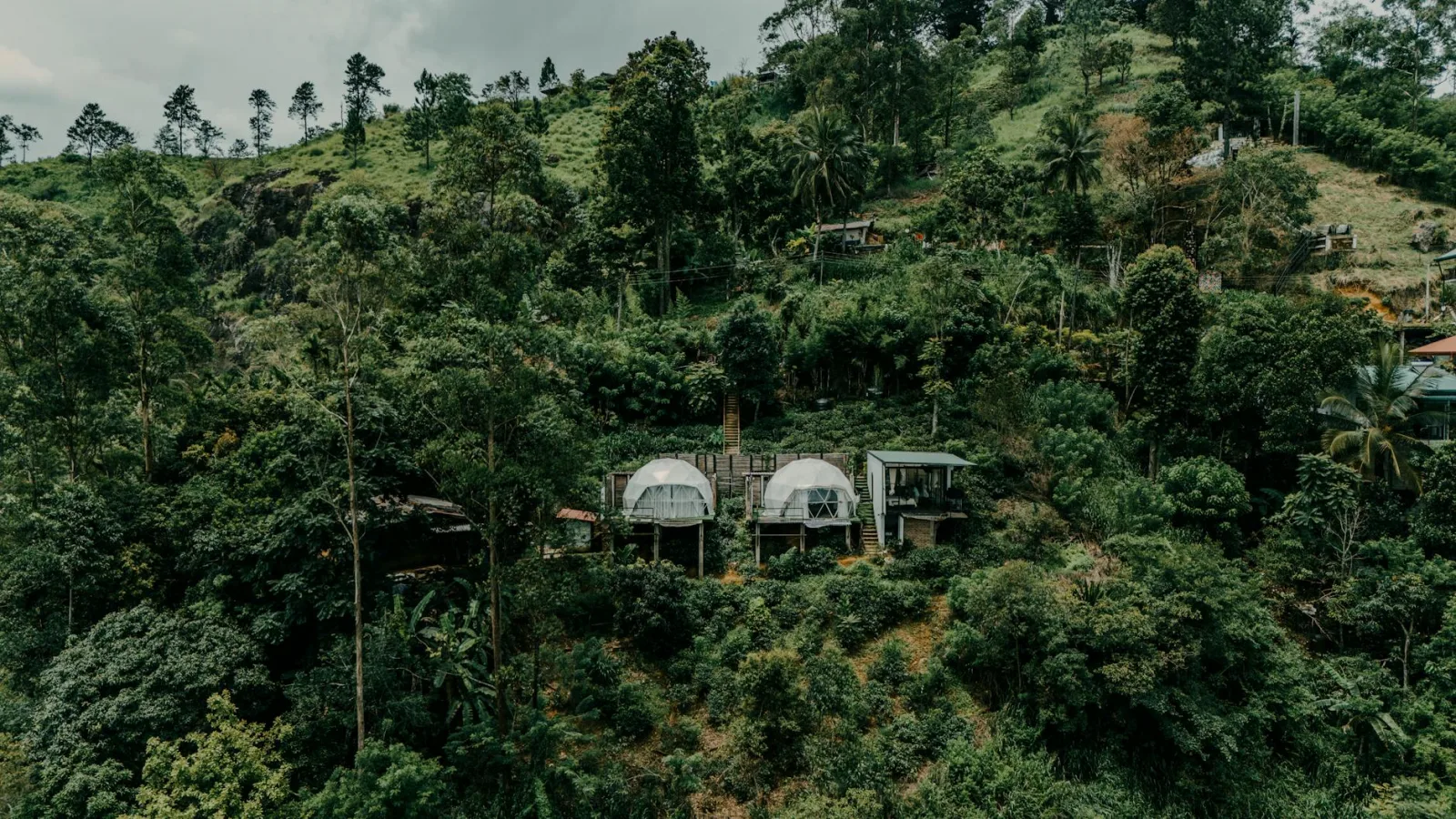 Aerial shot of eco-friendly huts nestled in lush greenery in the Sri Lankan hills, perfect for eco-travelers.