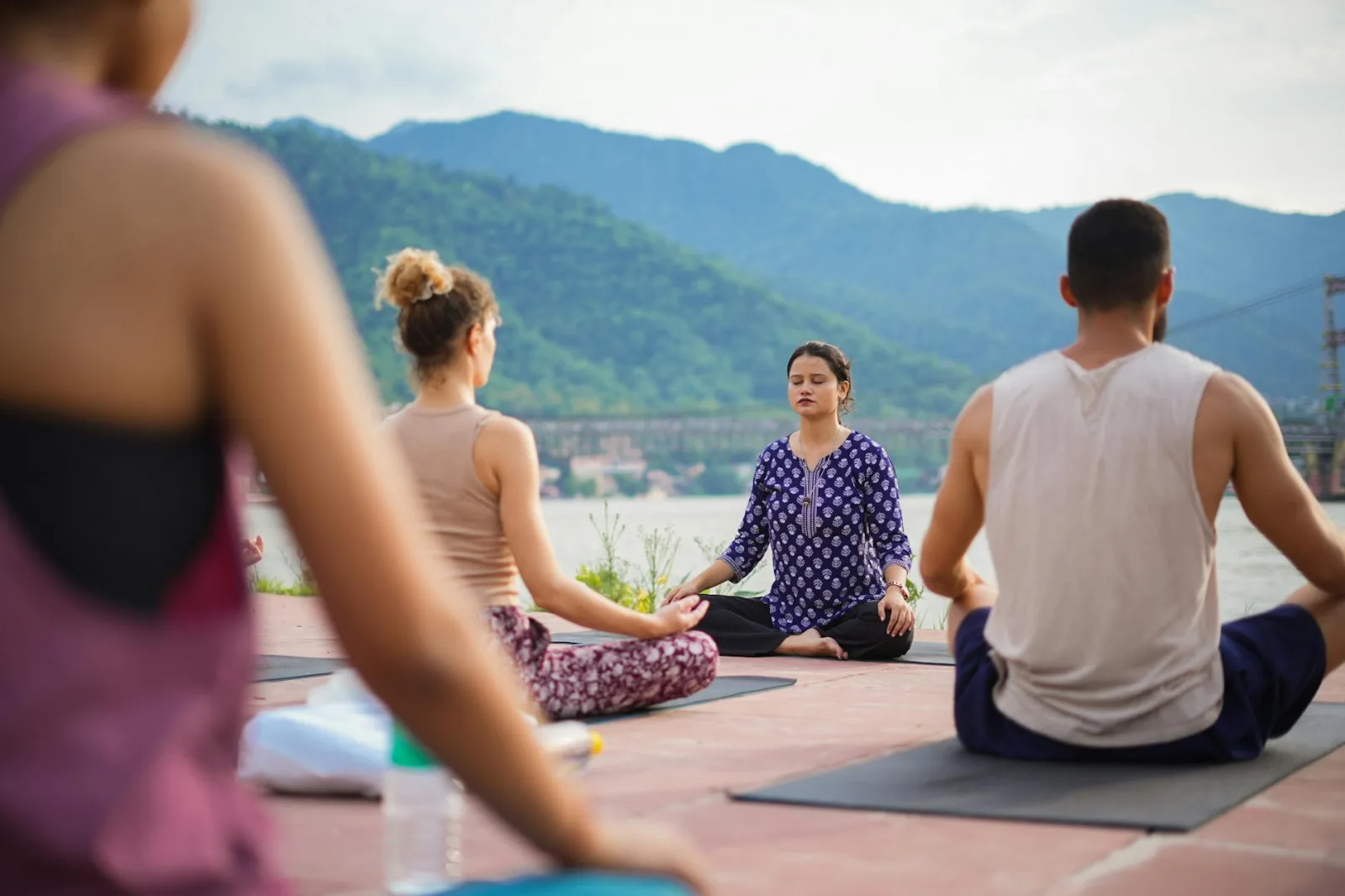 A group practicing yoga outdoors by the Ganges River in Rishikesh, India.
