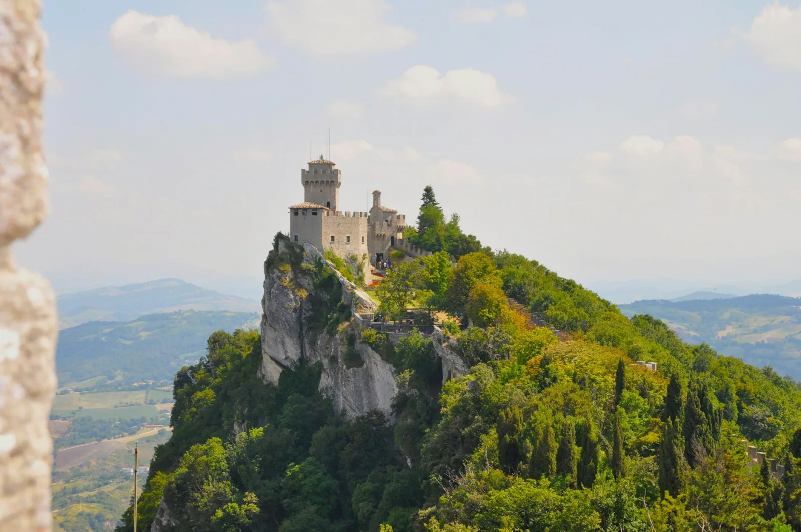 Discover the enchanting hilltop castle surrounded by lush greenery in San Marino.