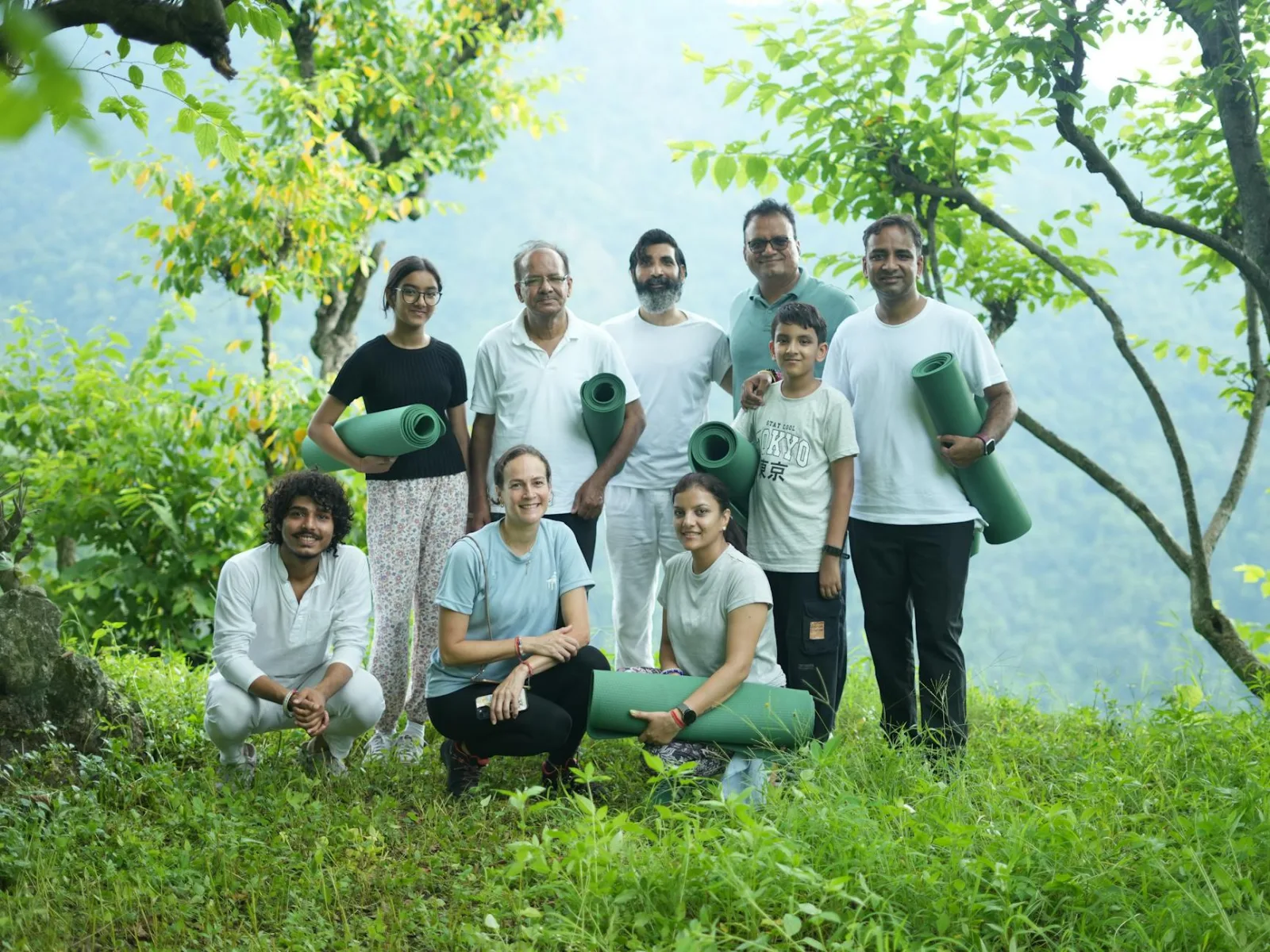 A diverse group enjoying an outdoor yoga retreat in the serene greenery of Rishikesh, India.