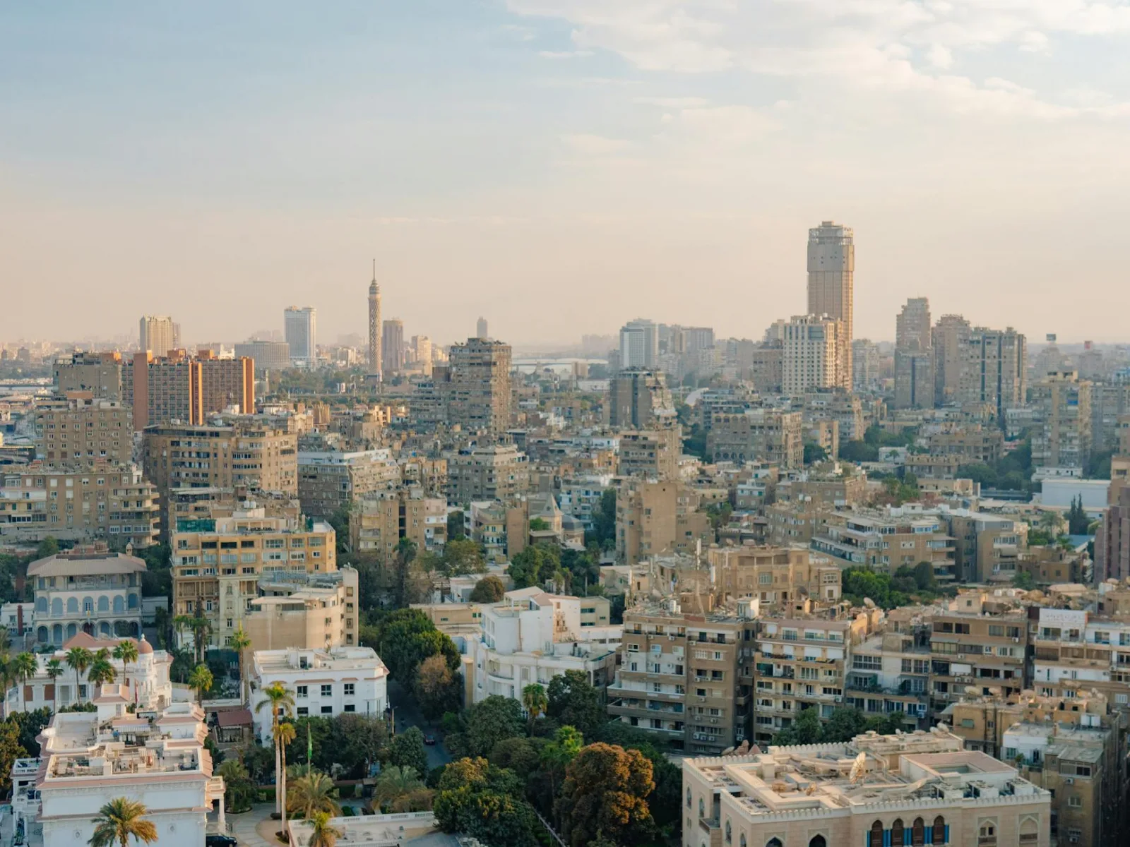 Aerial view of Cairo's urban skyline featuring prominent buildings and the Cairo Tower at dusk.