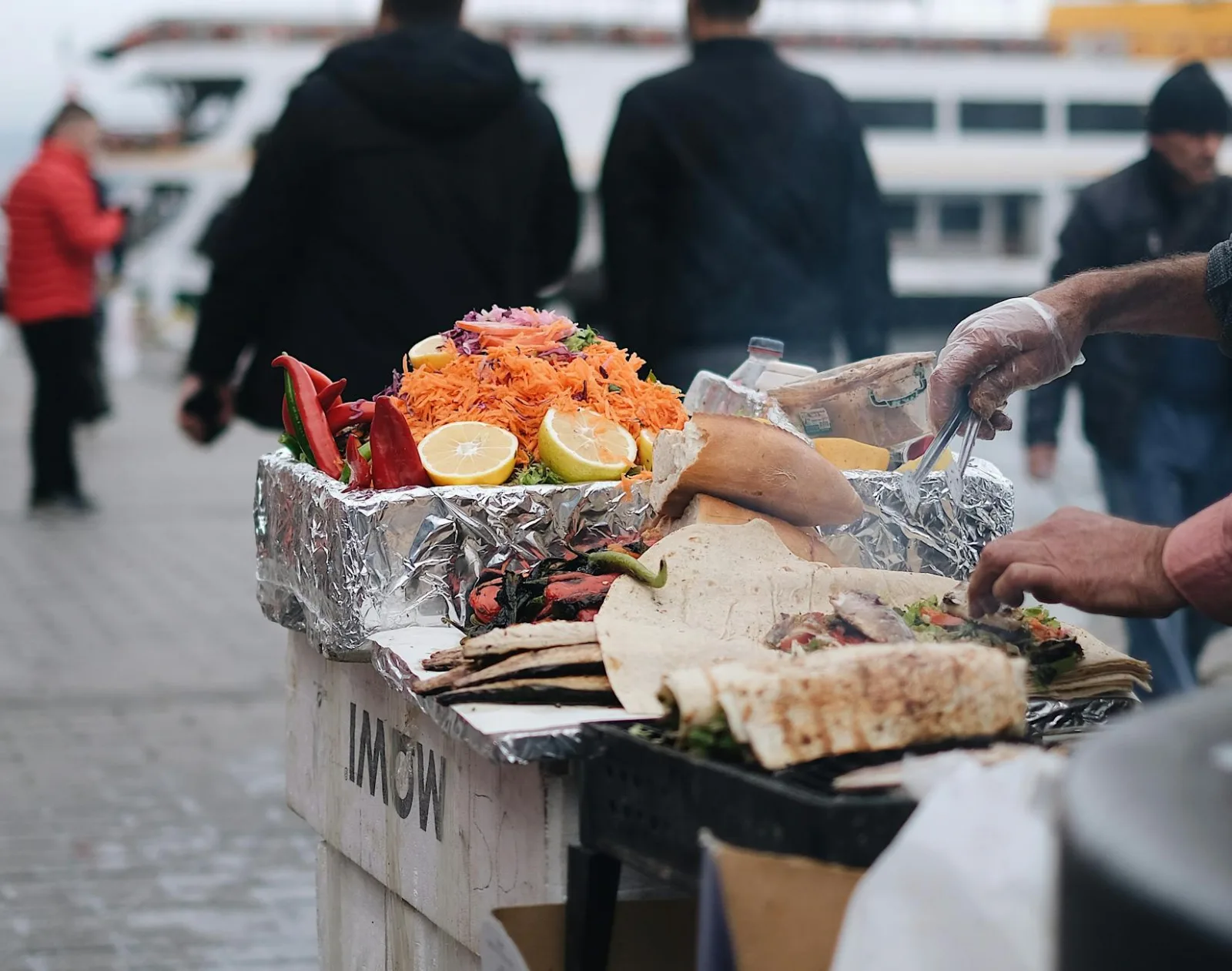 Close-up of a street food vendor preparing delicious grilled wraps with colorful vegetables and spices.