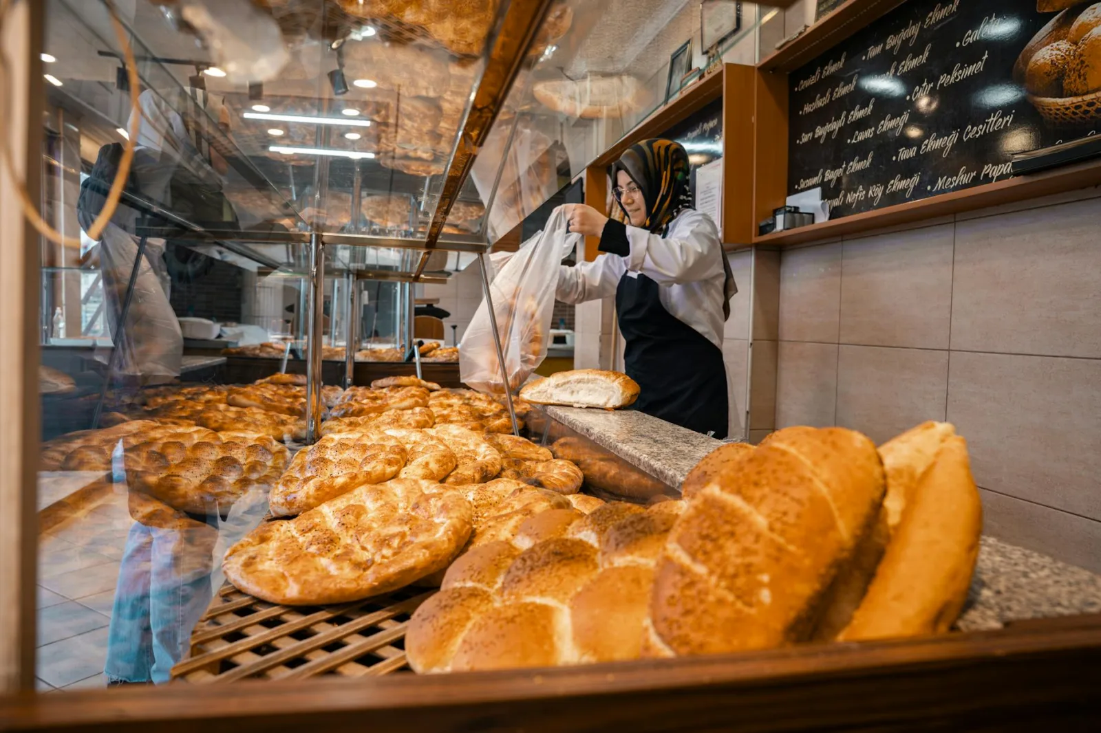 Baker packaging fresh, golden-brown bread in a vibrant bakery setting.