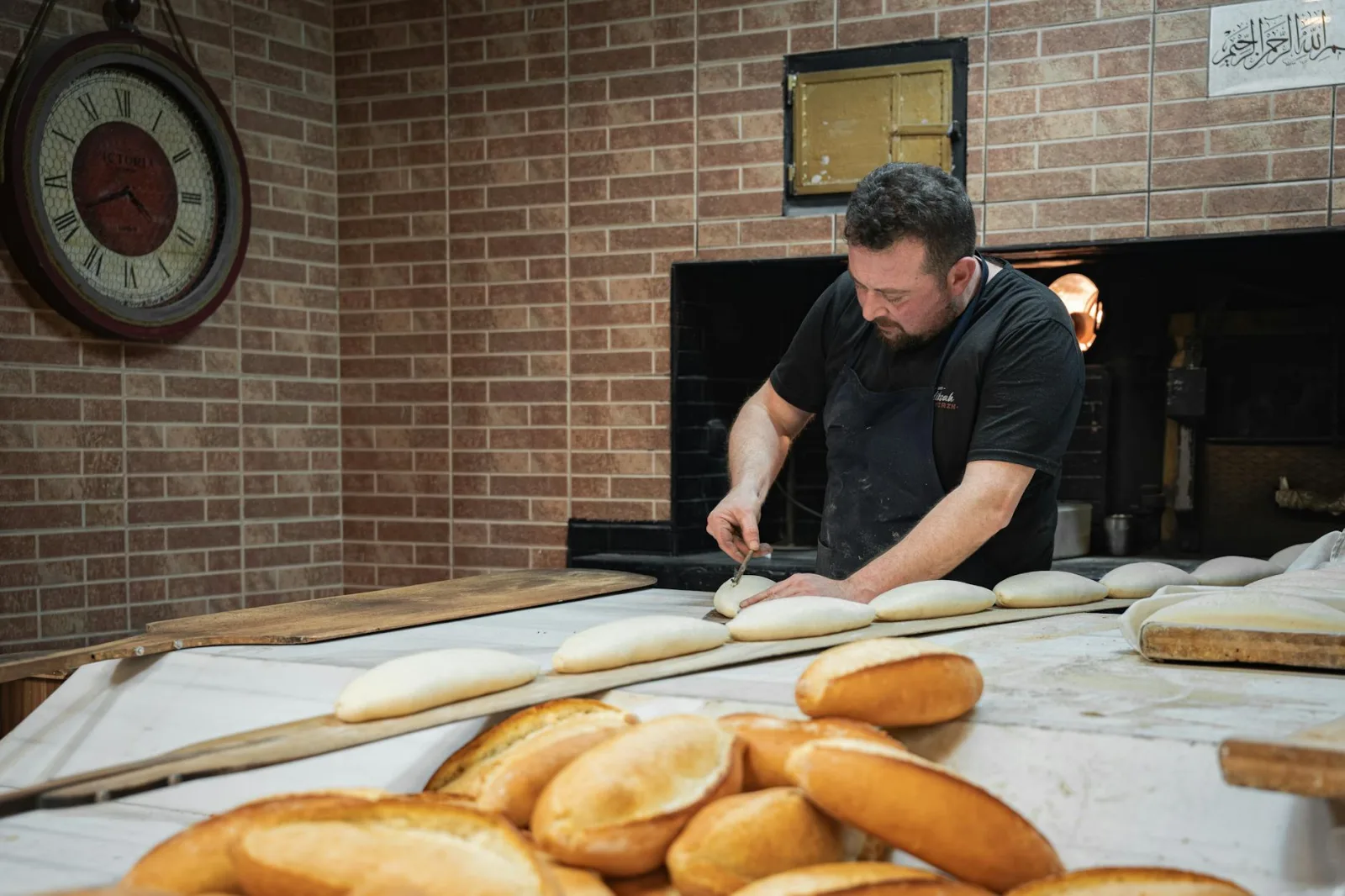Artisan baker preparing bread in a traditional bakery setting, wearing an apron.