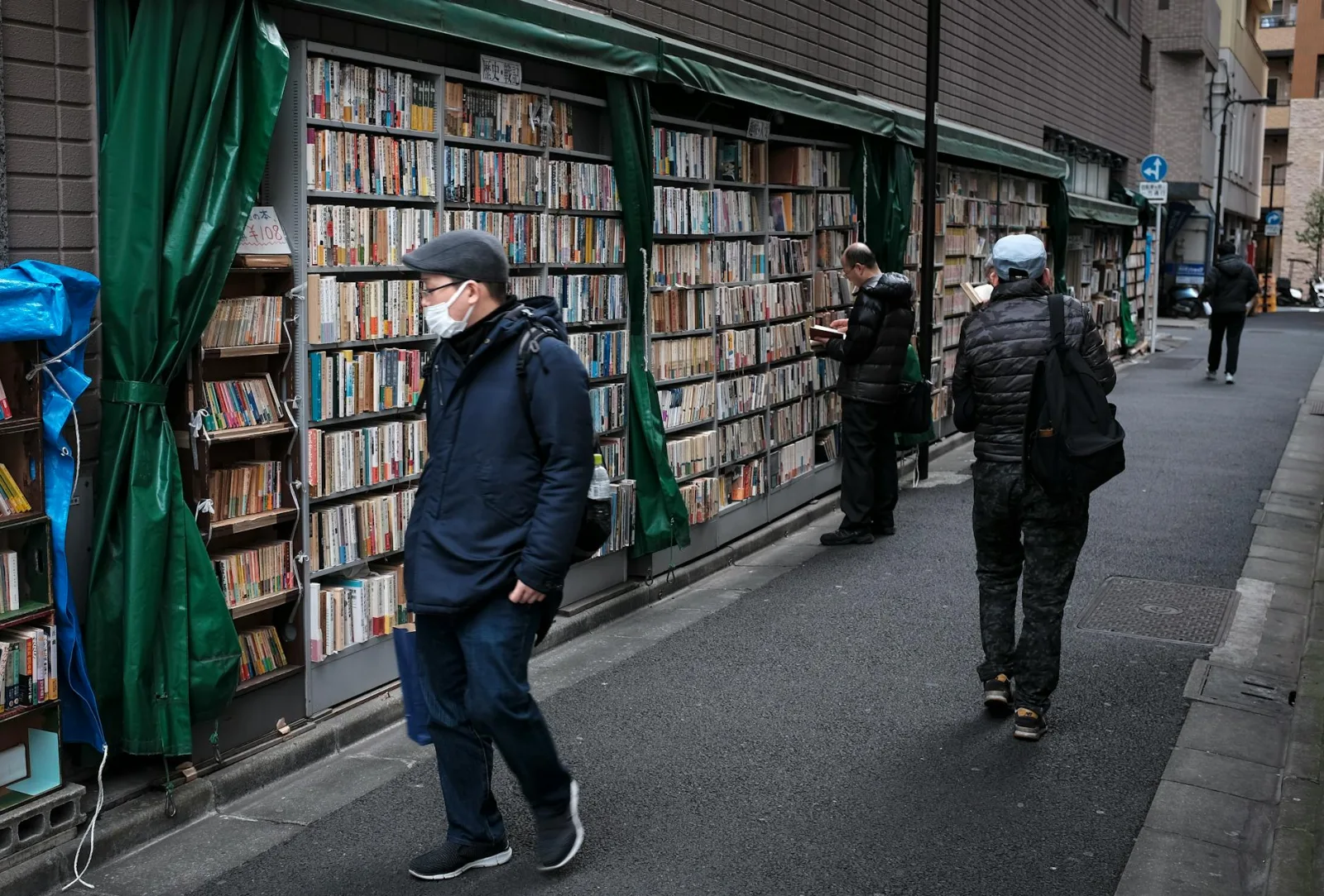 People browsing street bookstore in a Tokyo alley, showcasing everyday urban life.