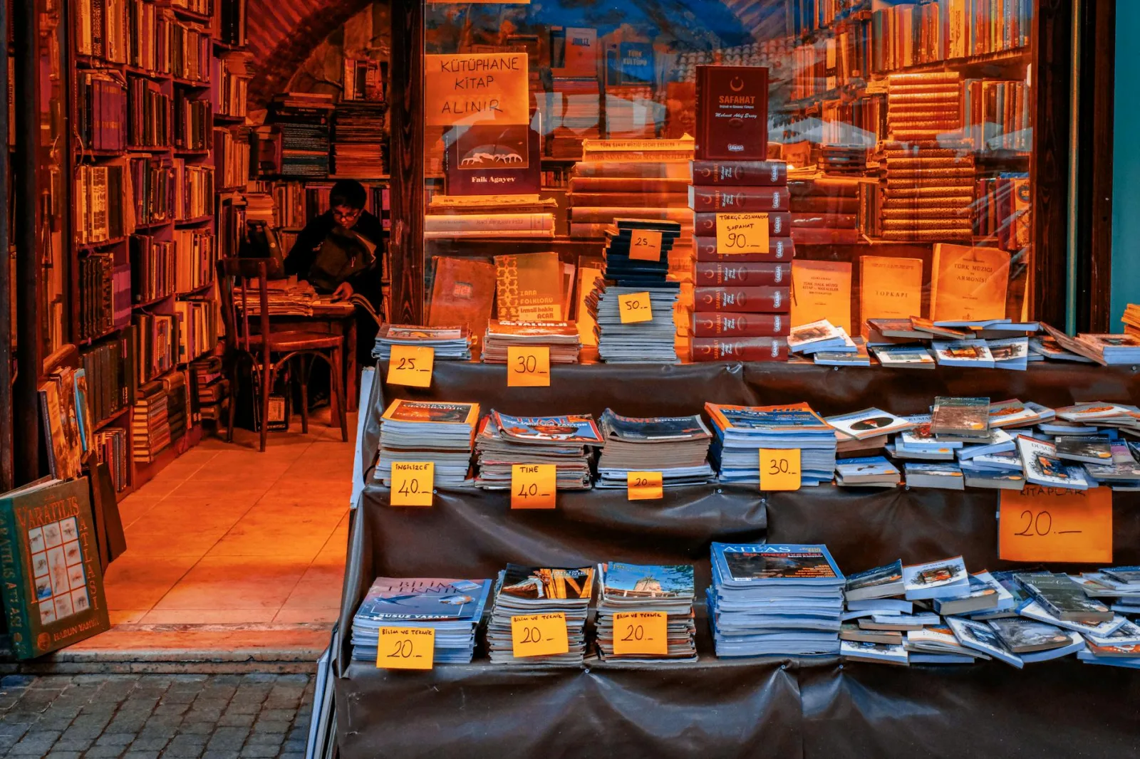 Warmly lit bookstore featuring an eclectic mix of vintage books with price tags in a quaint setting.