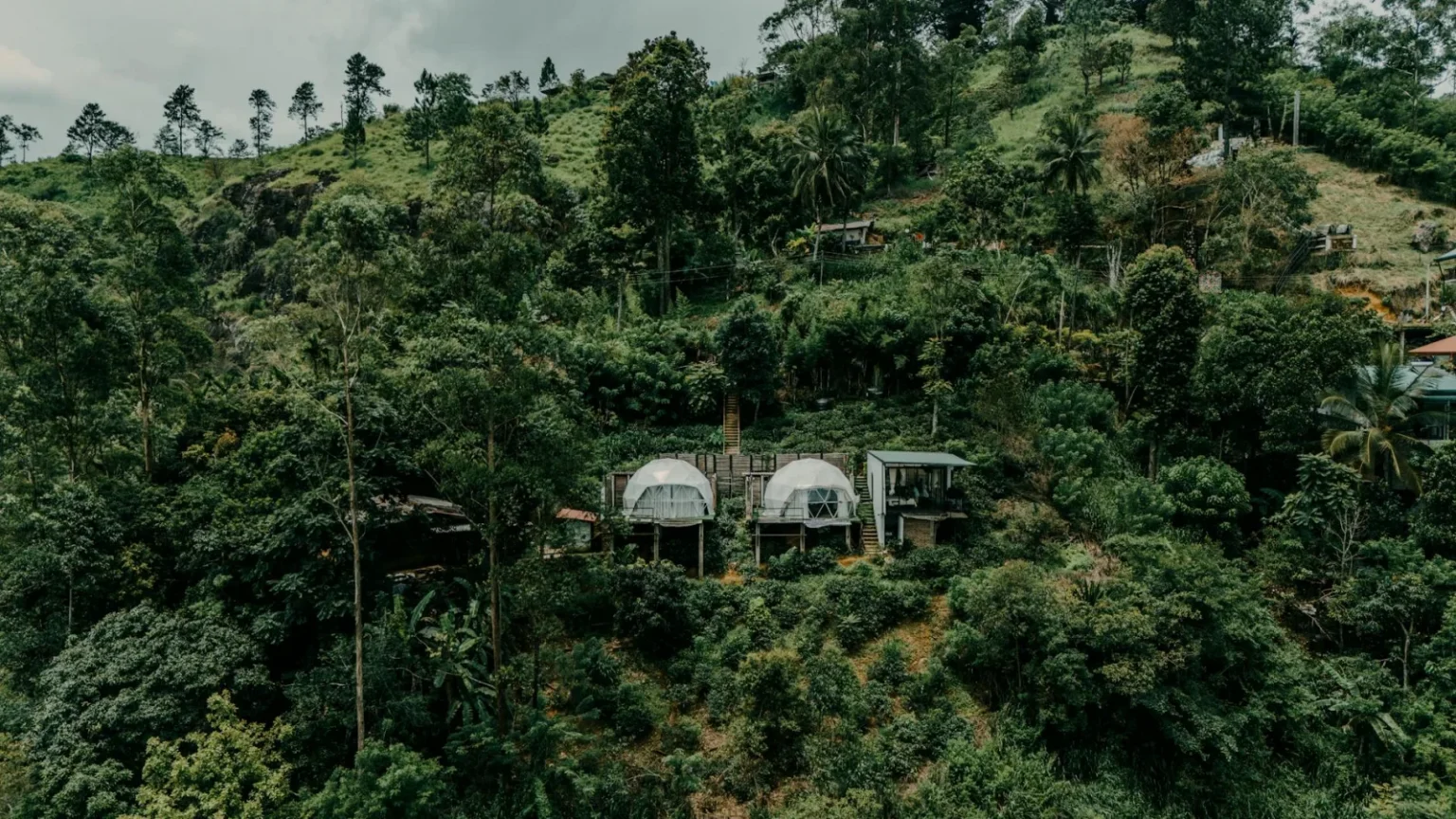 Aerial shot of eco-friendly huts nestled in lush greenery in the Sri Lankan hills, perfect for eco-travelers.