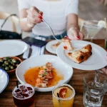 Friends enjoying a casual meal sharing various dishes and drinks at a restaurant.