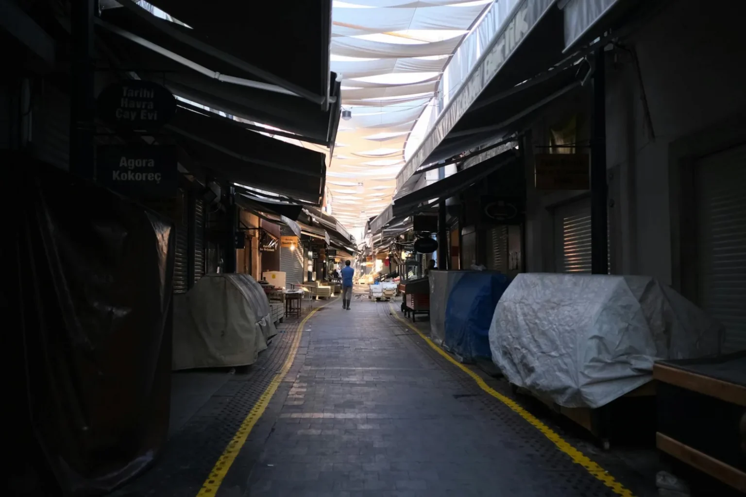 A quiet market alleyway with colorful canopies overhead, capturing an urban setting