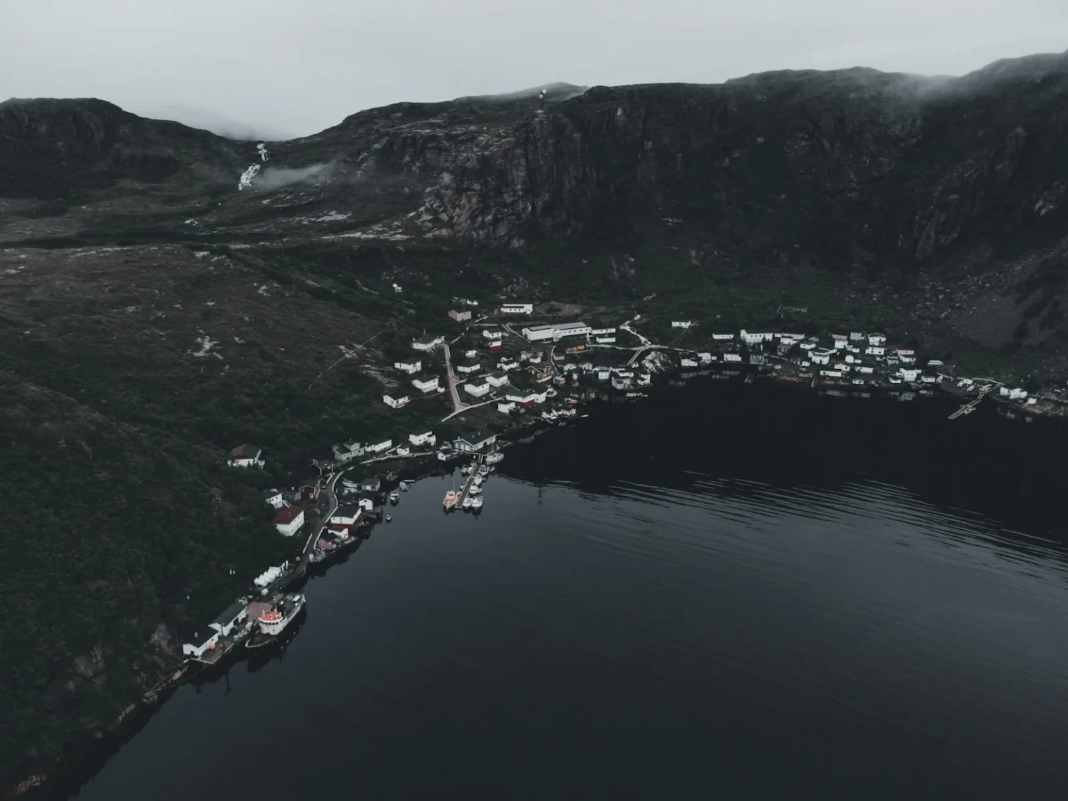 A serene aerial view of a foggy Norwegian coastal village surrounded by fjords.