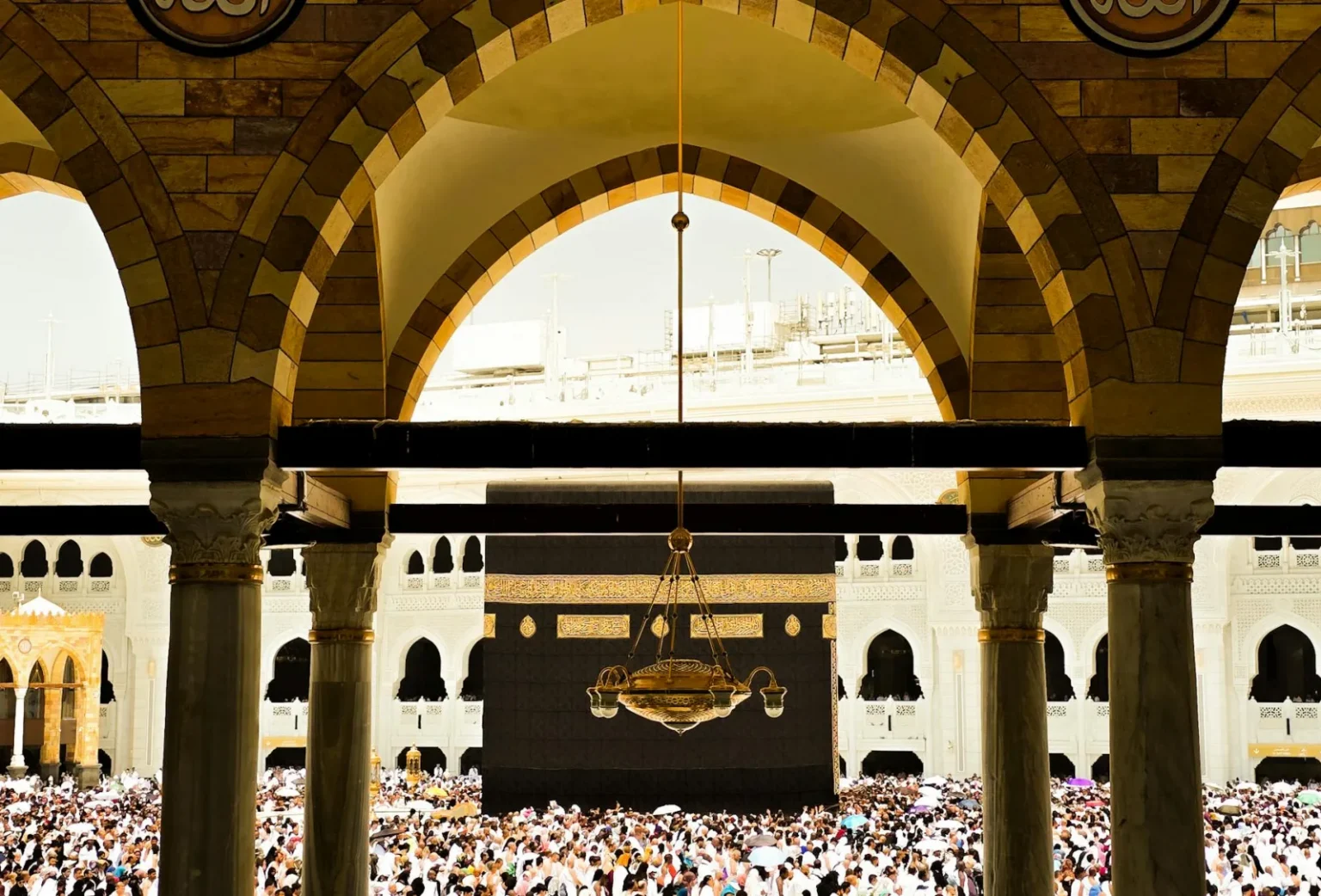 A crowded scene at the Kaaba within the Grand Mosque in Mecca, Saudi Arabia, during daytime.