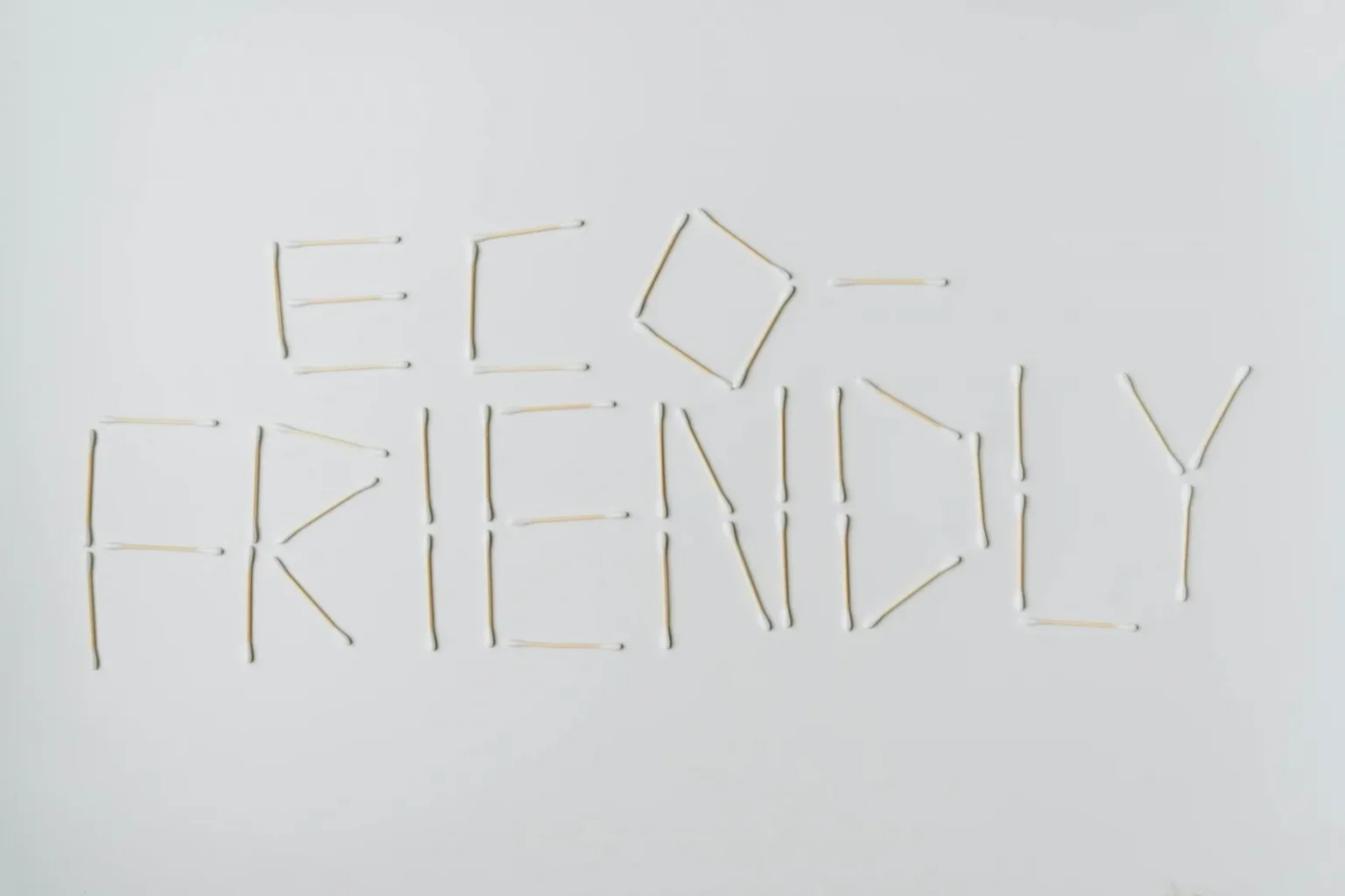 Cotton swabs spelling out "eco-friendly" on a clean white surface.