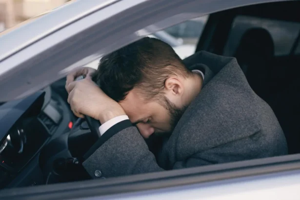 Man in car showing stress with head on steering wheel, highlighting emotional fatigue.