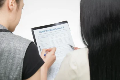 Two women examining home insurance policy form, focused on details.