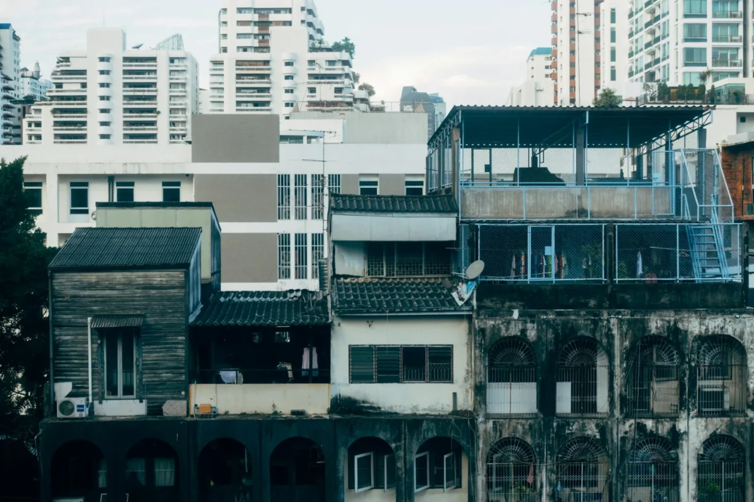 A juxtaposition of aging and modern urban buildings in a dense city landscape.