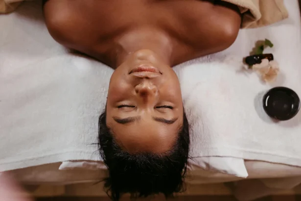 A woman enjoying a peaceful spa treatment, lying topless with eyes closed on a white towel.
