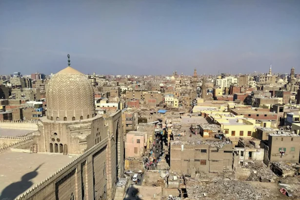 Aerial view of historic Old Cairo showcasing dense residential buildings and a prominent mosque dome under clear skies.