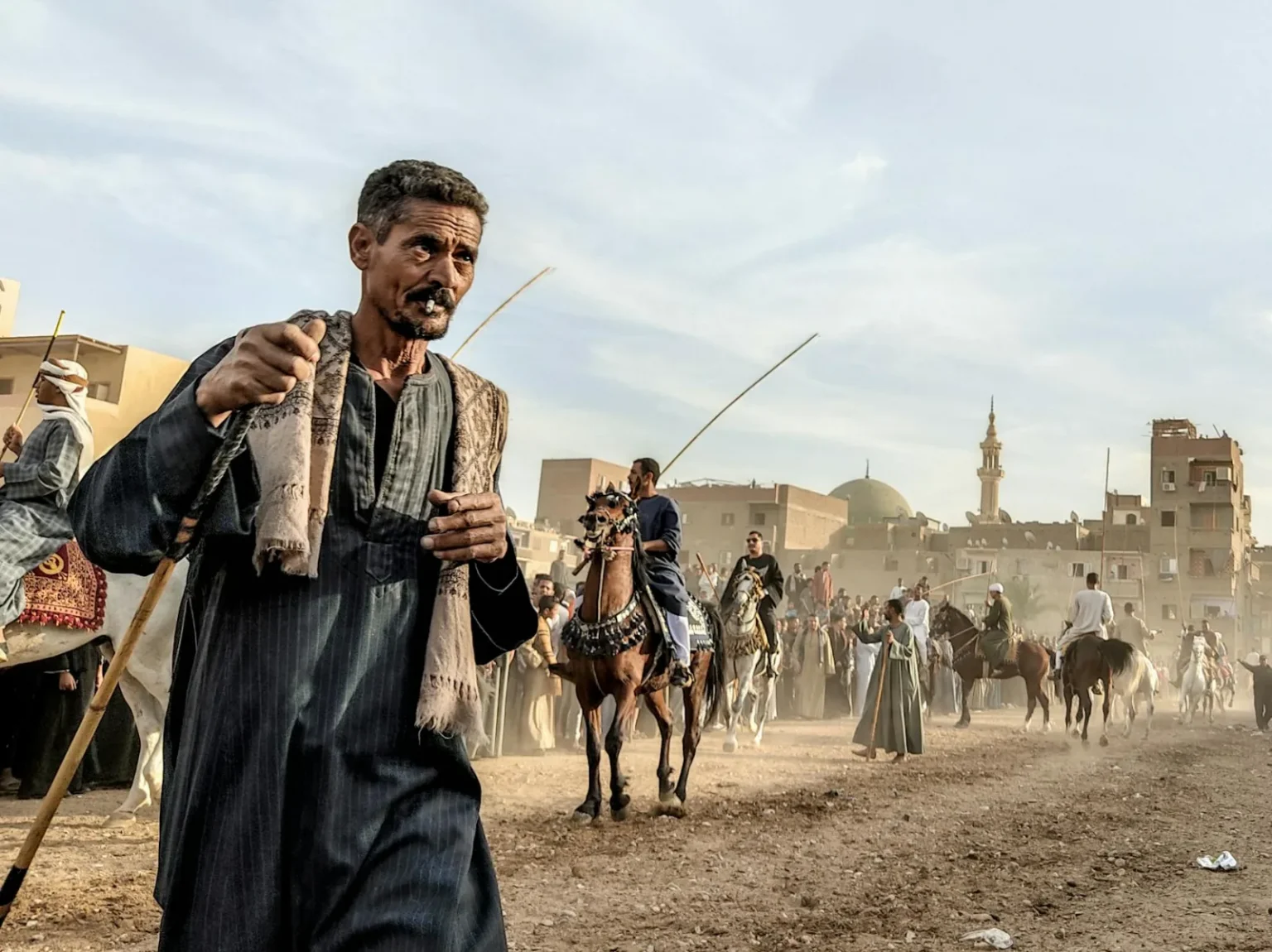 Men and horses at a traditional festival parade in Egypt, showcasing cultural heritage and equestrian skills.