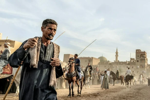 Men and horses at a traditional festival parade in Egypt, showcasing cultural heritage and equestrian skills.