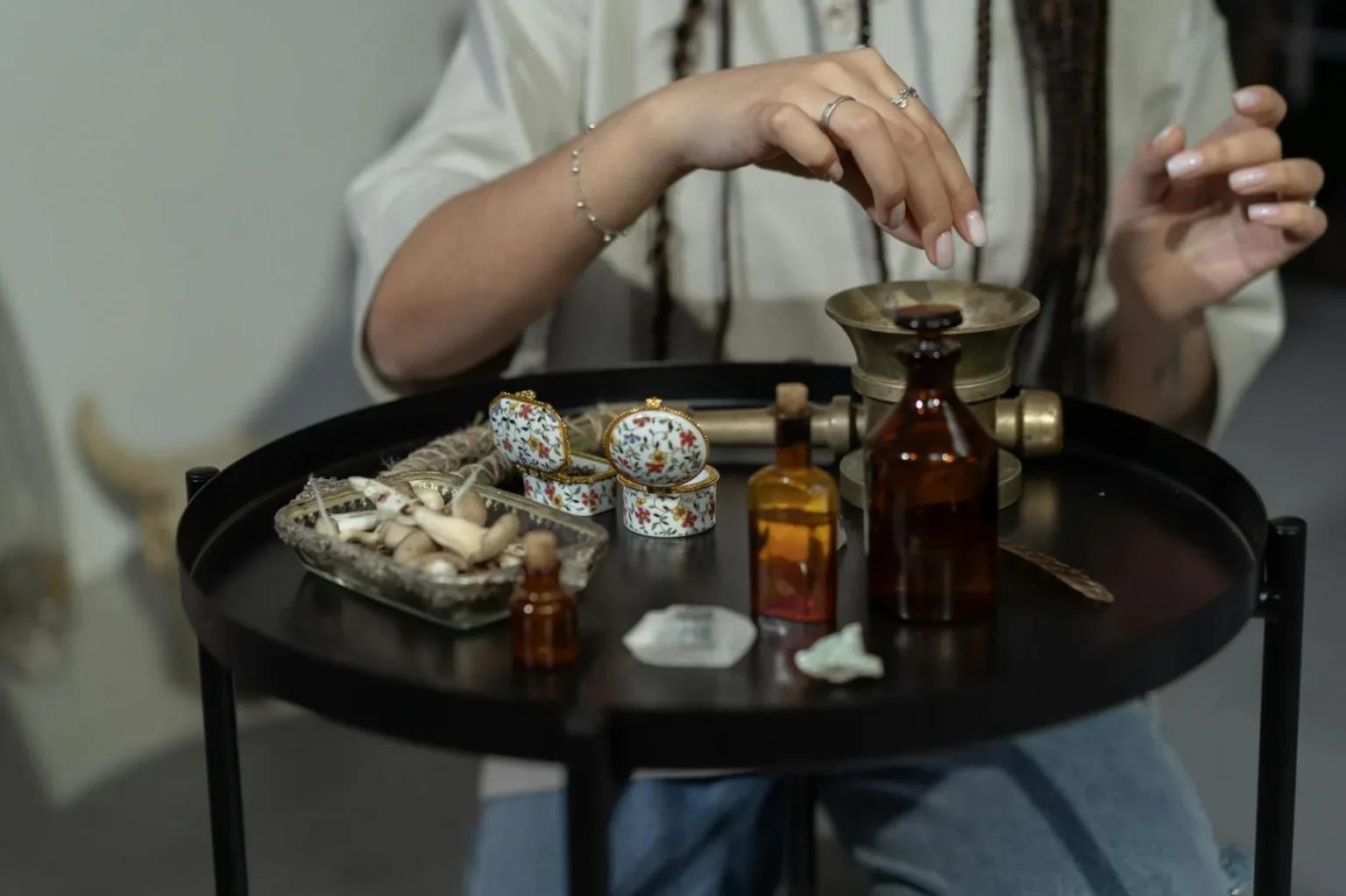 A hand engaging in a spiritual ritual with herbs and bottles on a mystical table.