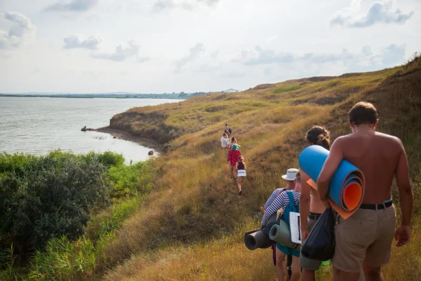 A group of people hiking along a beautiful riverbank in Russia, near Ахтанизовская.
