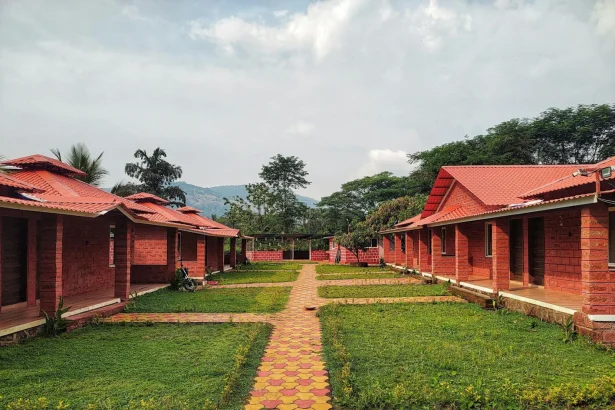 Picturesque red brick bungalows lined along lush gardens with scenic mountain views.