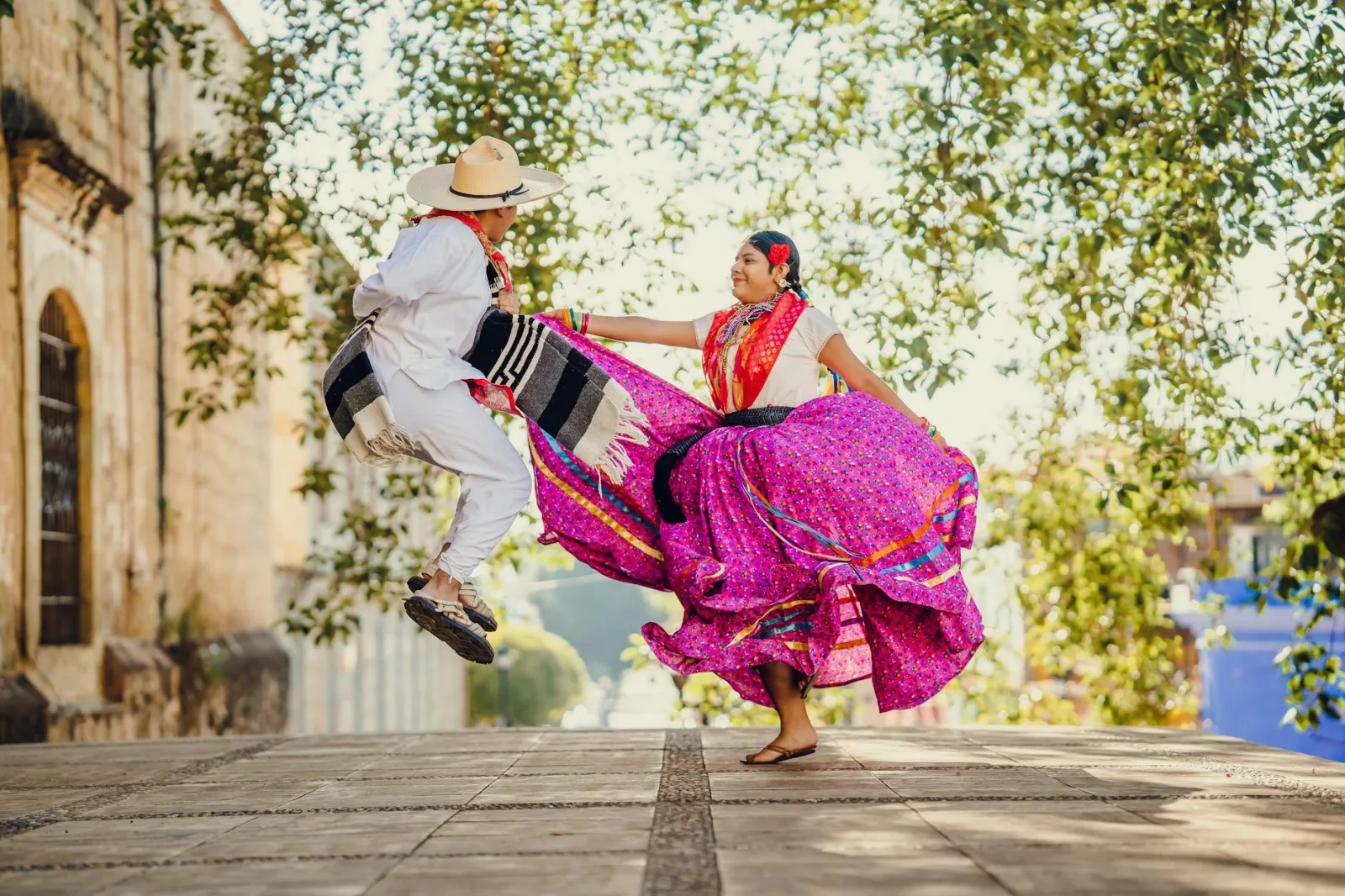 A colorful tradition unfolds with dancers in vibrant attire celebrating in the streets of Oaxaca, Mexico.