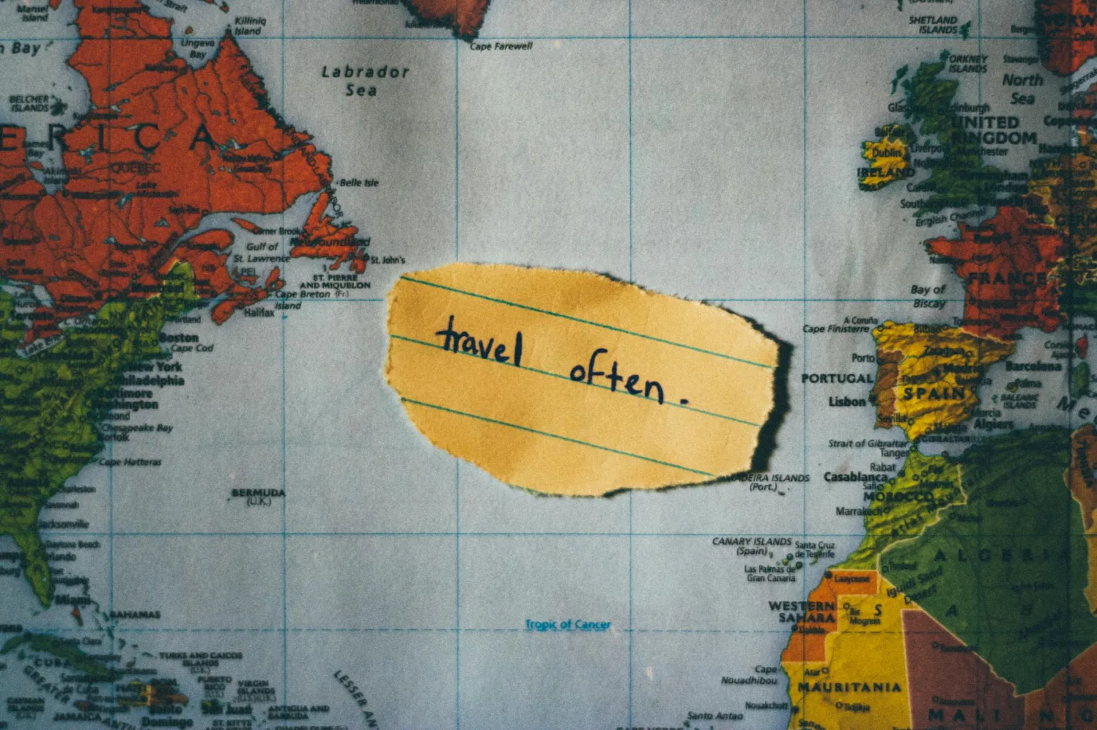 A motivating note 'travel often' placed over a colorful world map, inspiring exploration.