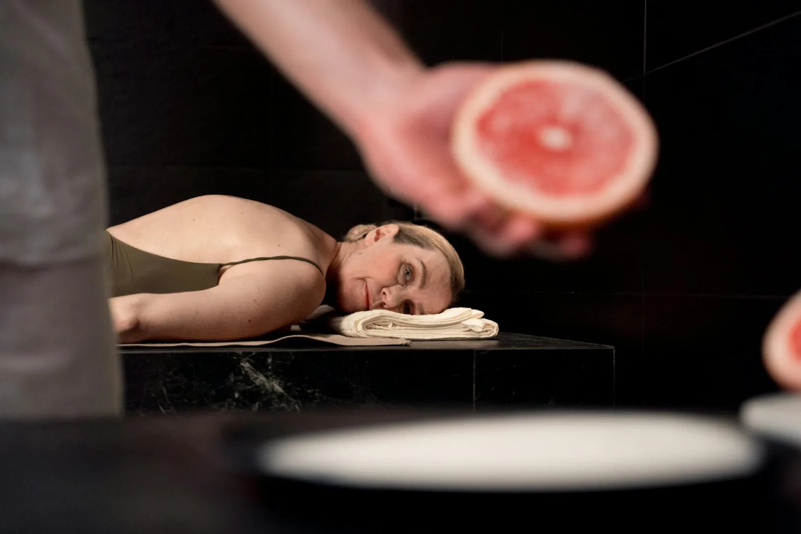 Senior woman relaxing in a spa with a focus on grapefruit wellness treatment.