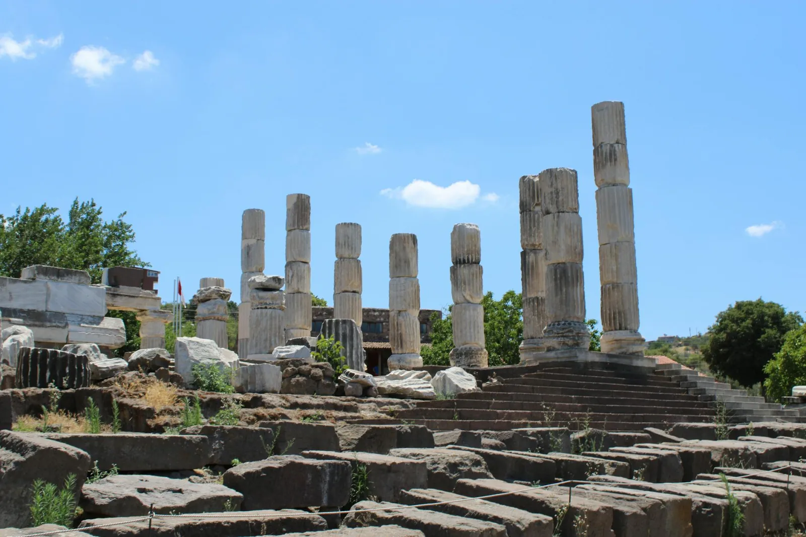 Ancient archaeological site with tall columnar ruins beneath a clear blue sky.