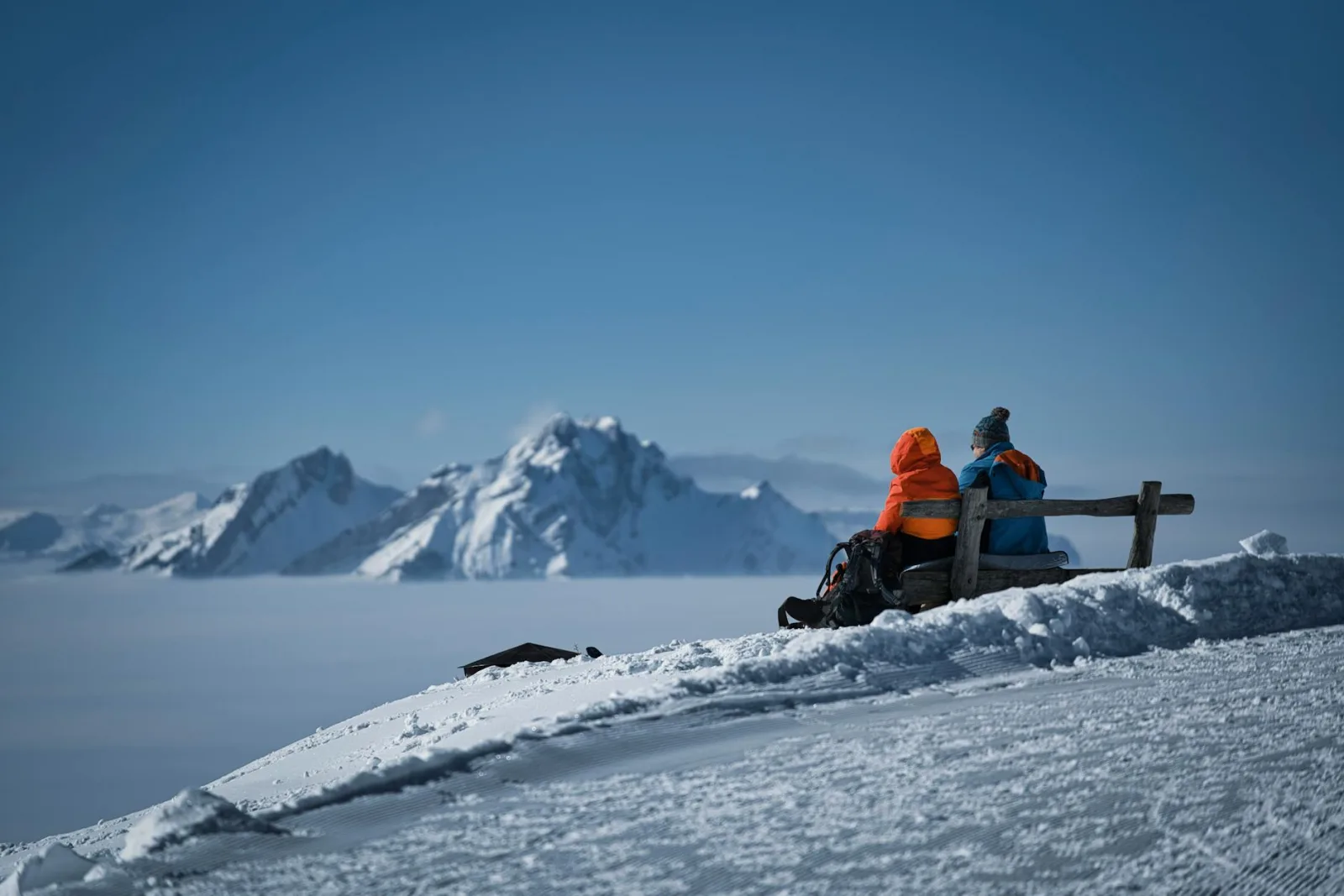 Two climbers rest on a snowy mountain with a breathtaking view, capturing the essence of adventure.