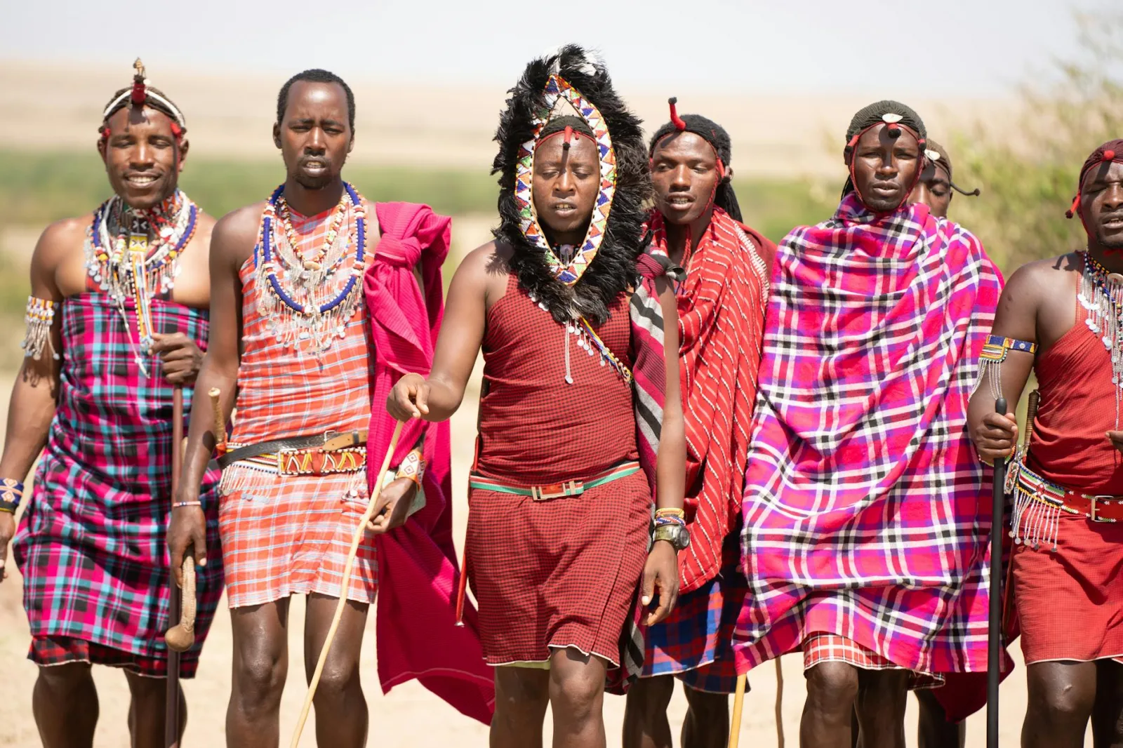 Group of Maasai men in traditional attire walking in the Kenyan landscape.