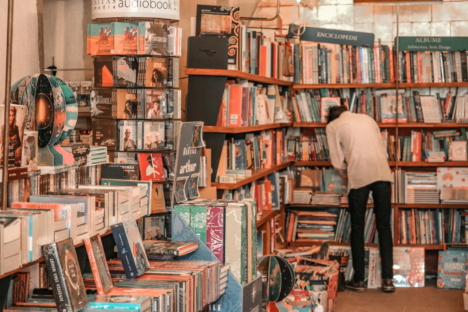 A person browses a vibrant selection of books in a cozy Brașov bookstore.