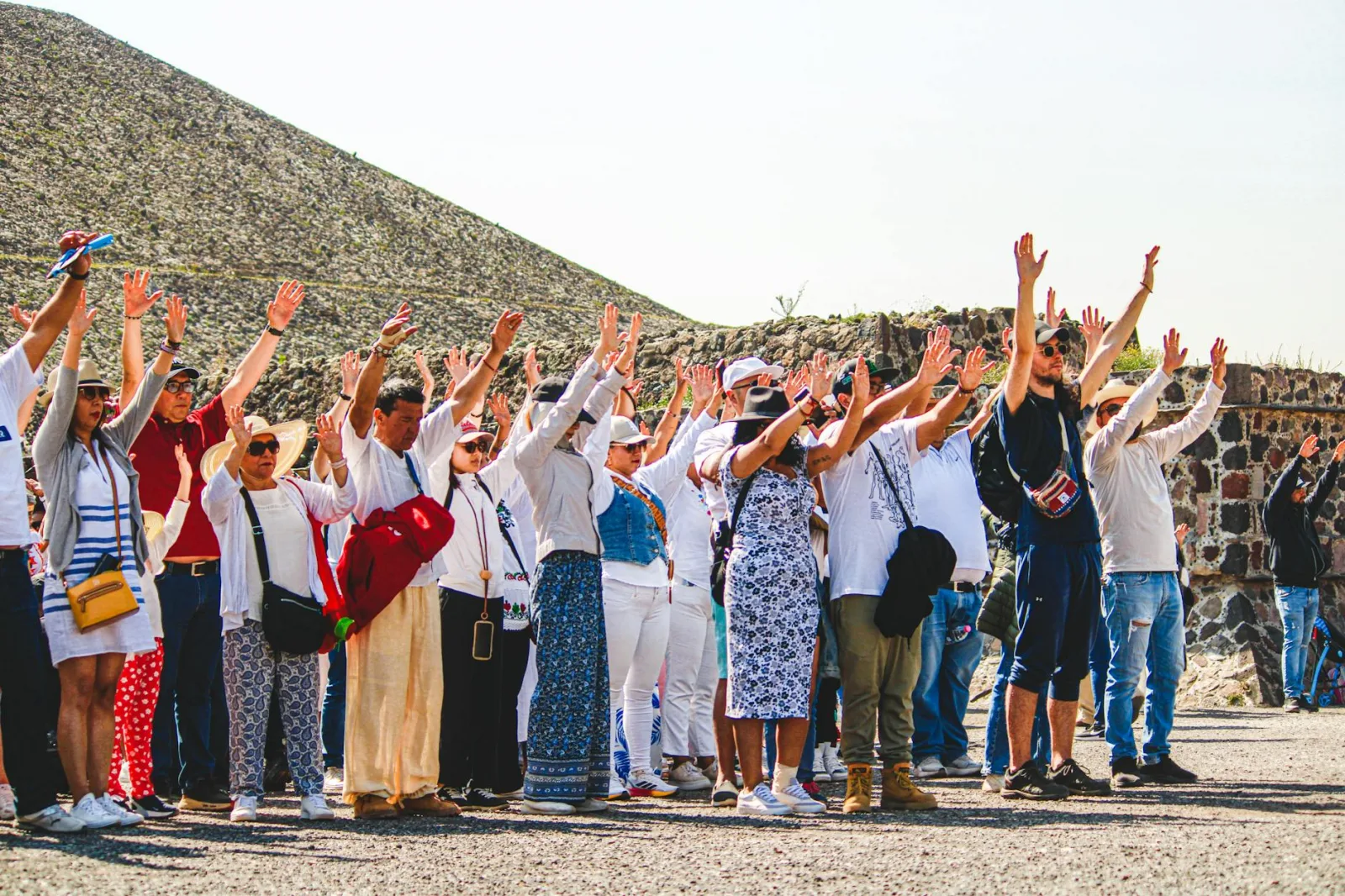 A group of tourists raising hands at the Pyramids of Teotihuacán, Mexico.