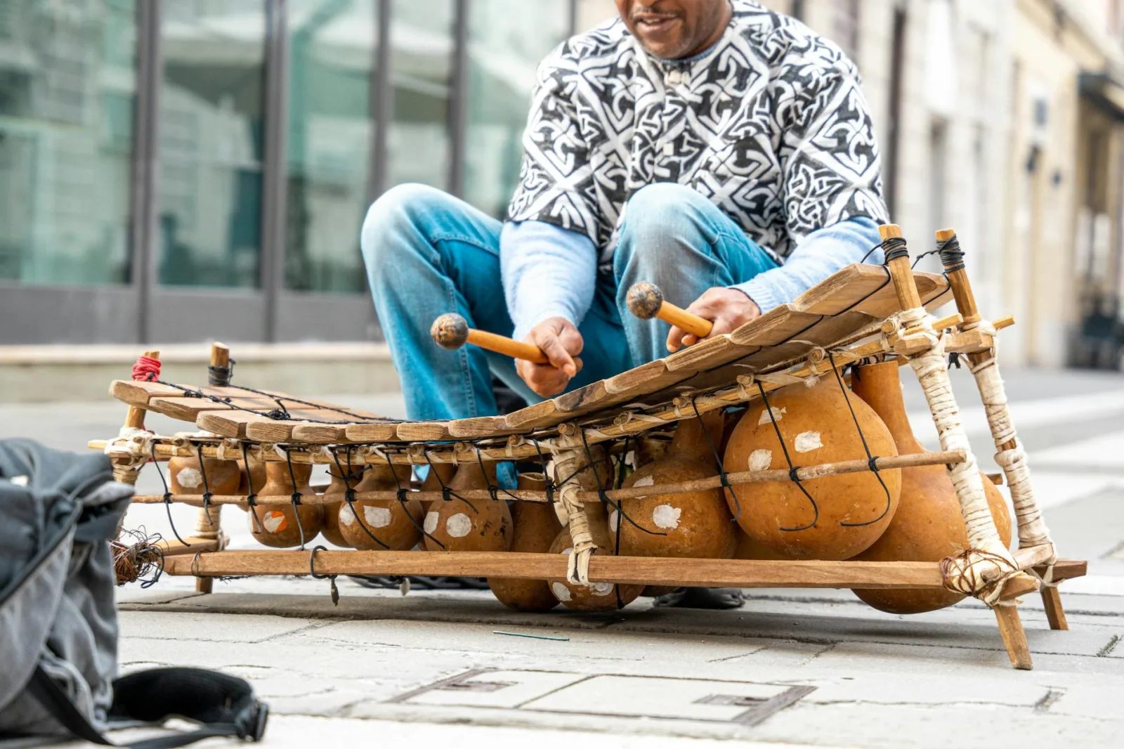 A street musician playing a traditional African balafon in an urban setting.