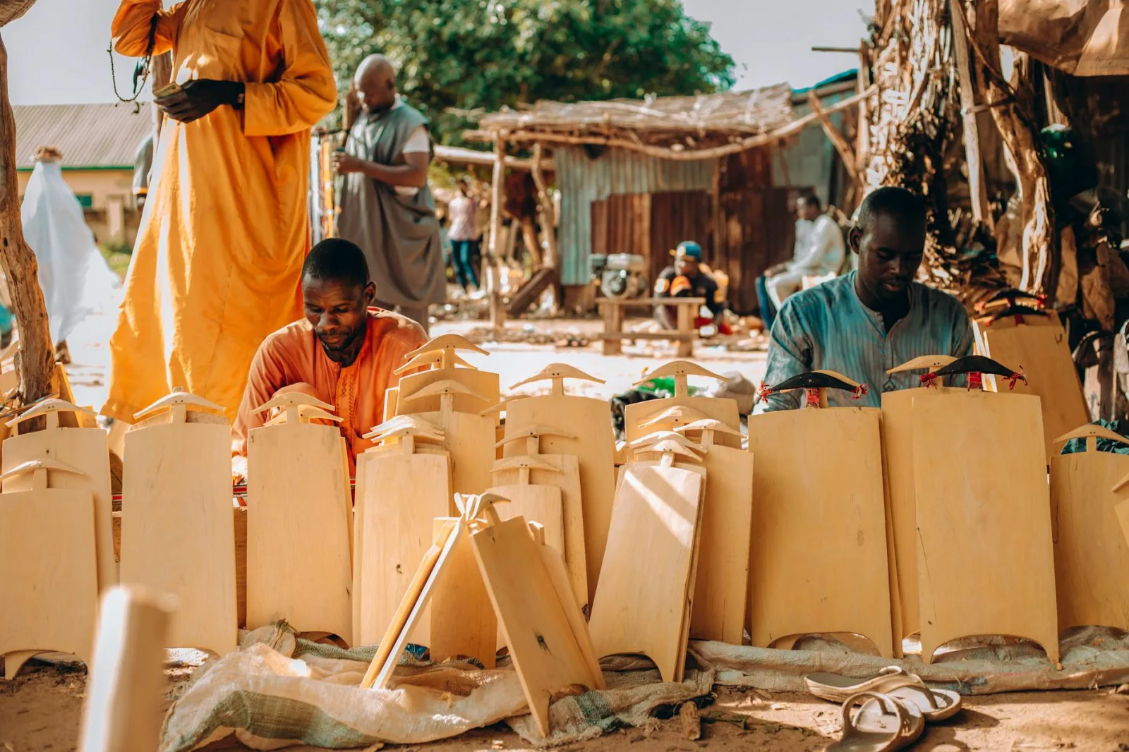 Artisans at work crafting wooden items in an outdoor market setting, showcasing traditional craftsmanship.