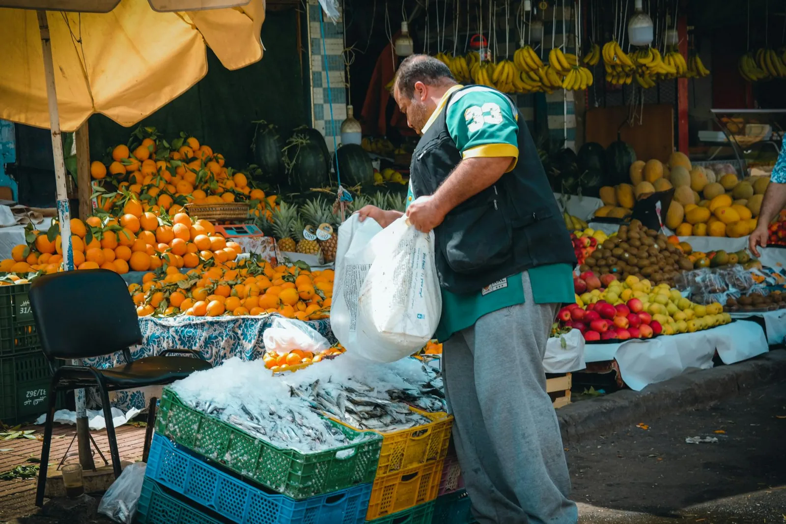 A lively Moroccan street market stall showcasing fresh fruits and seafood with a local merchant.