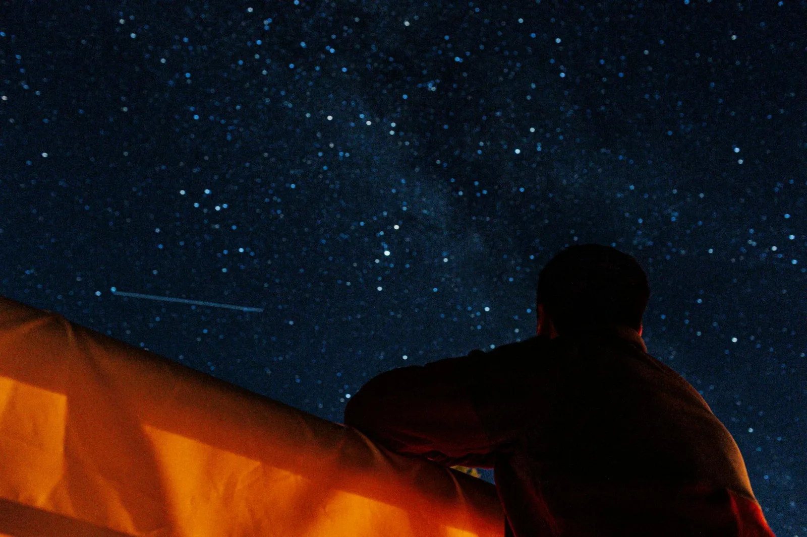 A person enjoys stargazing under a clear, starry night sky, capturing the beauty of the Milky Way.
