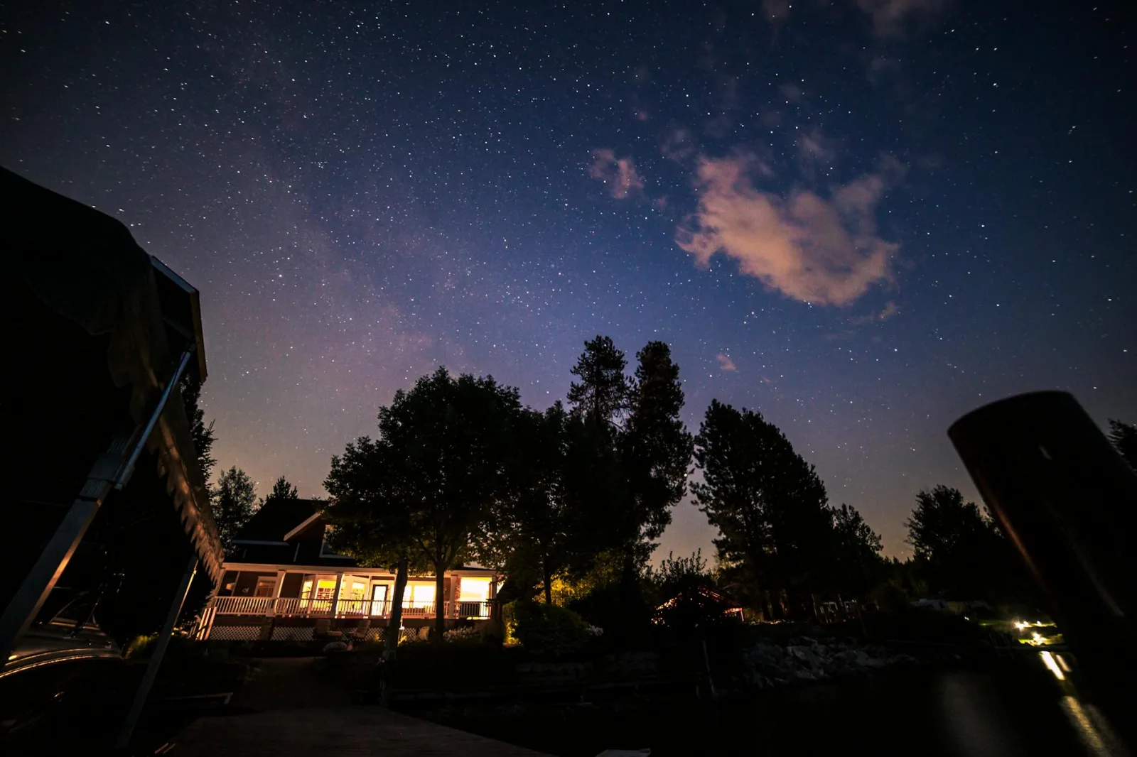 A tranquil view of a star-filled night sky over a lakeside house, capturing nature's beauty.