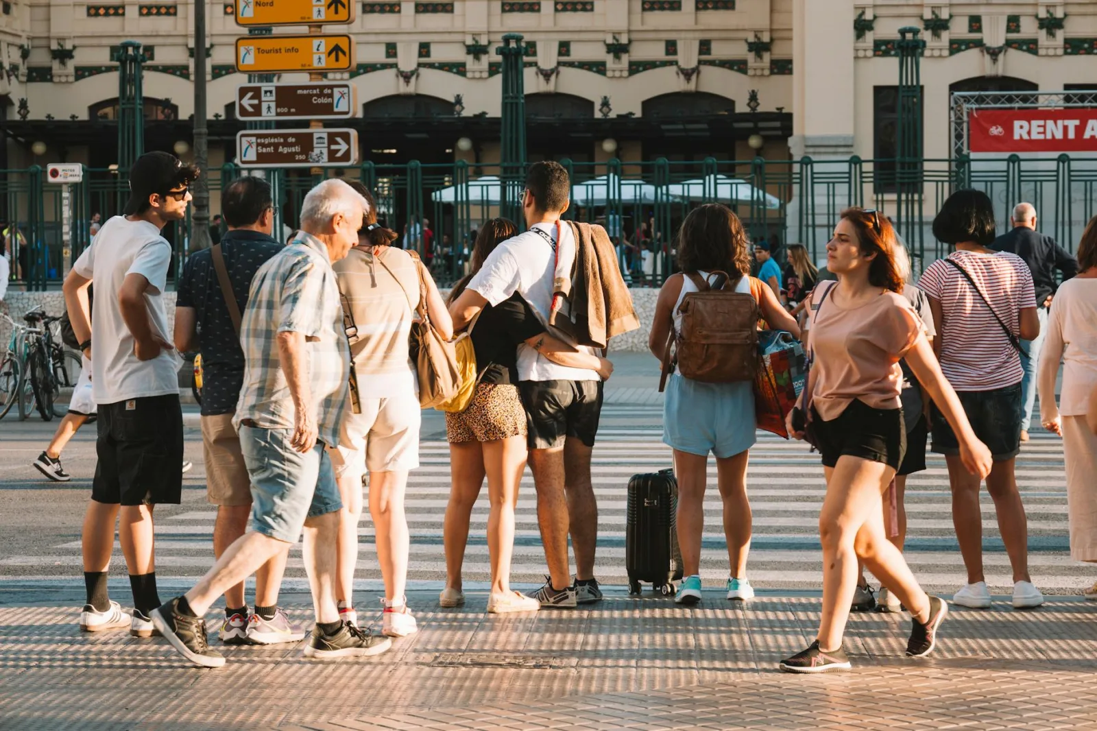 A busy crosswalk in Barcelona with diverse people crossing under warm sunlight.