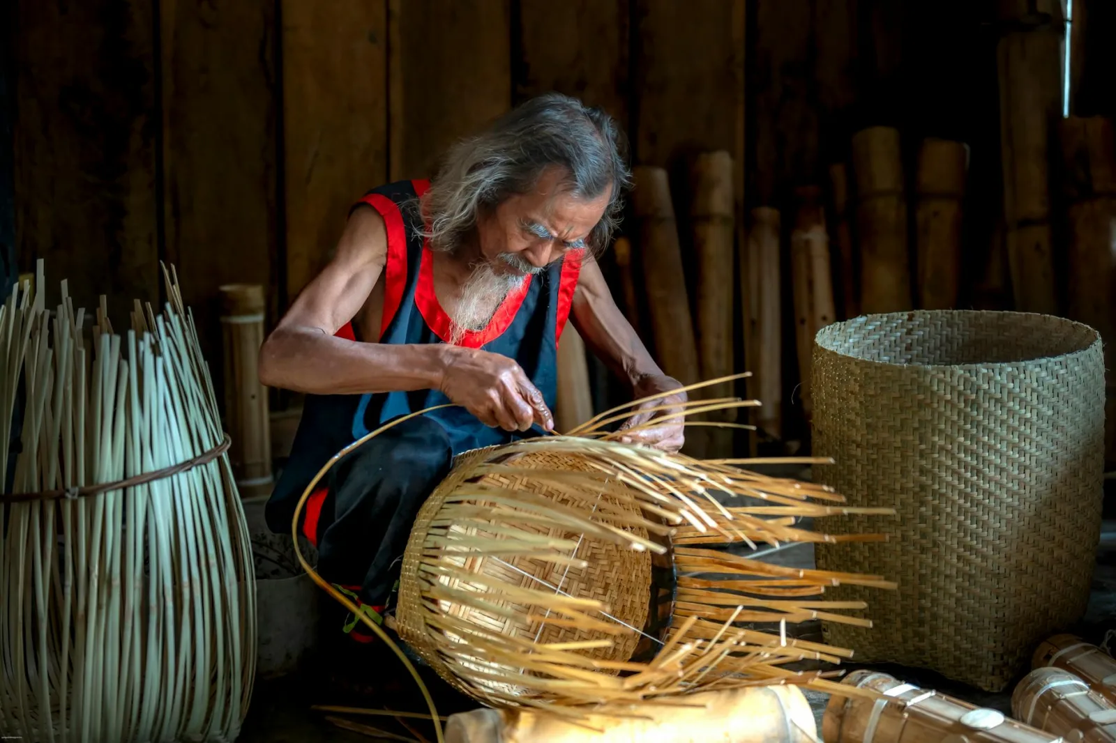 An elderly craftsman intricately weaving a bamboo basket in a traditional setting. Skillful hands at work.