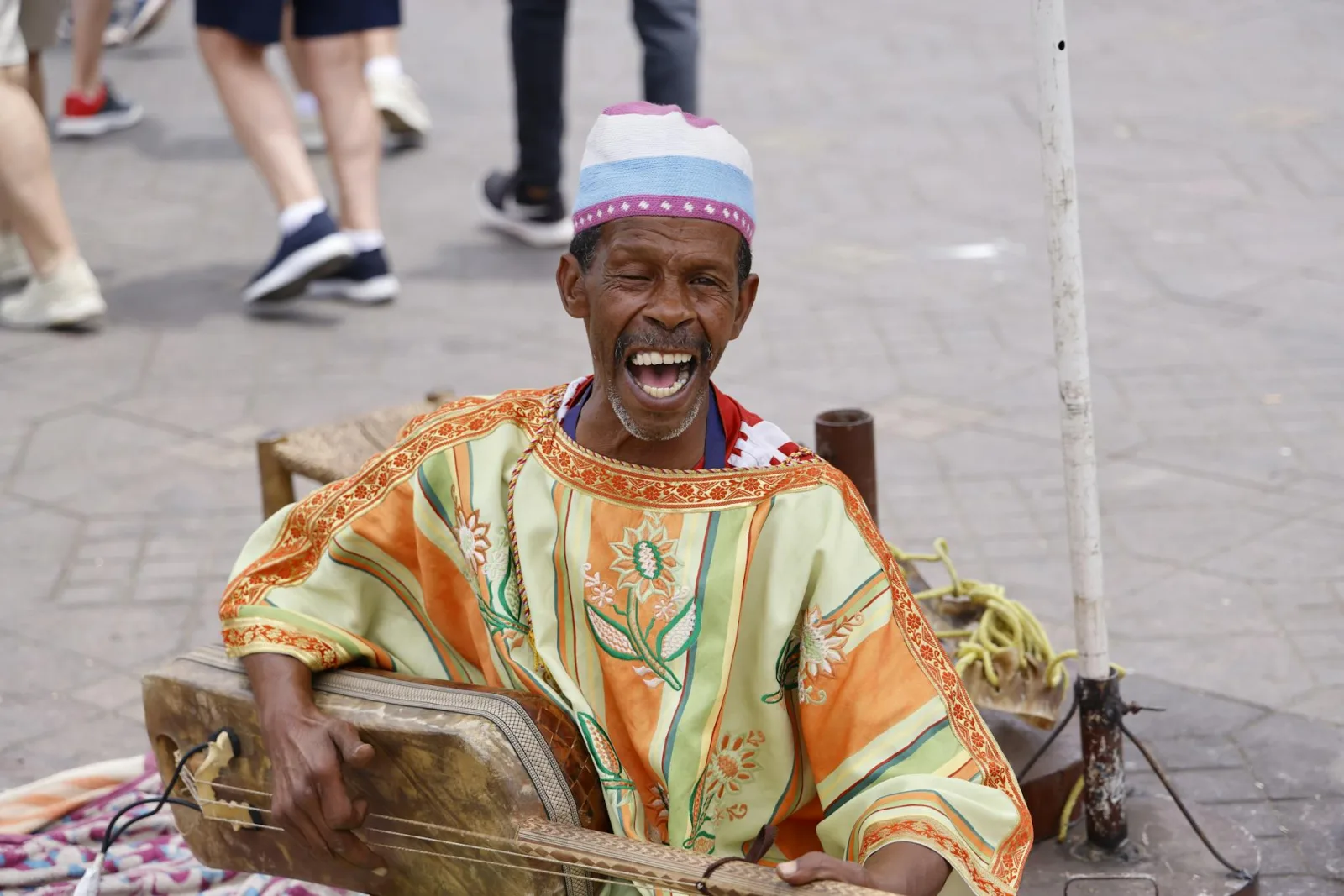A vibrant portrait of a Gnawa musician singing and playing an instrument on the streets of Morocco.